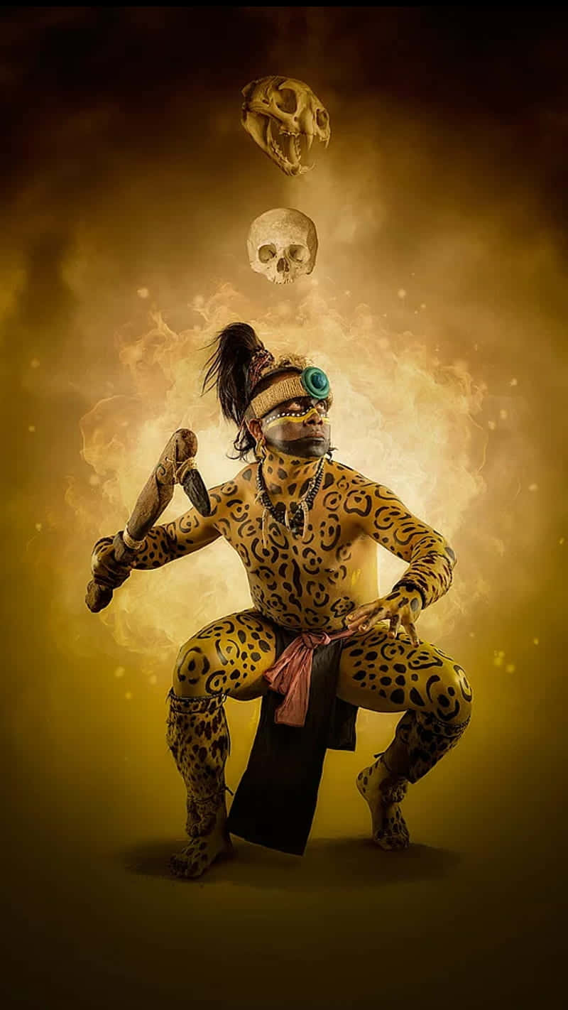 桌布 壁紙 — 一個身上塗有美洲豹圖案顏料的人戲劇性地蹲下，骷髏頭在煙霧瀰漫的金色背景下漂浮在他們上方。