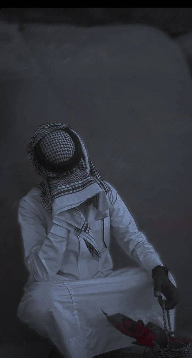 一個穿著傳統服飾的男人在昏暗的環境中手持念珠。 — 憂鬱男孩 壁紙