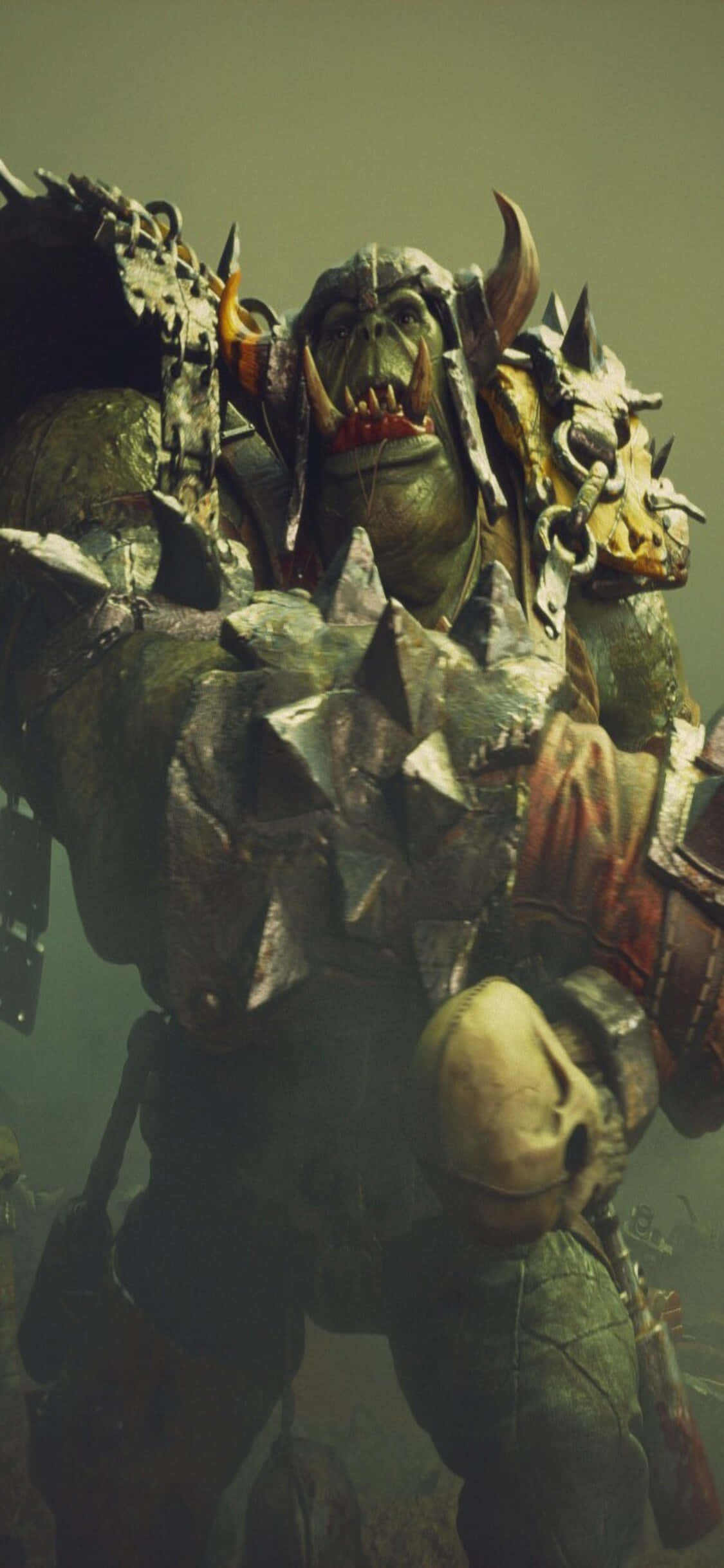 iPhone X Dawn Of War Iii 桌布 壁紙 — 一個身穿尖刺盔甲的高大獸人戰士，雙眼發光，手持骷髏裝飾的武器，兇猛咆哮。
