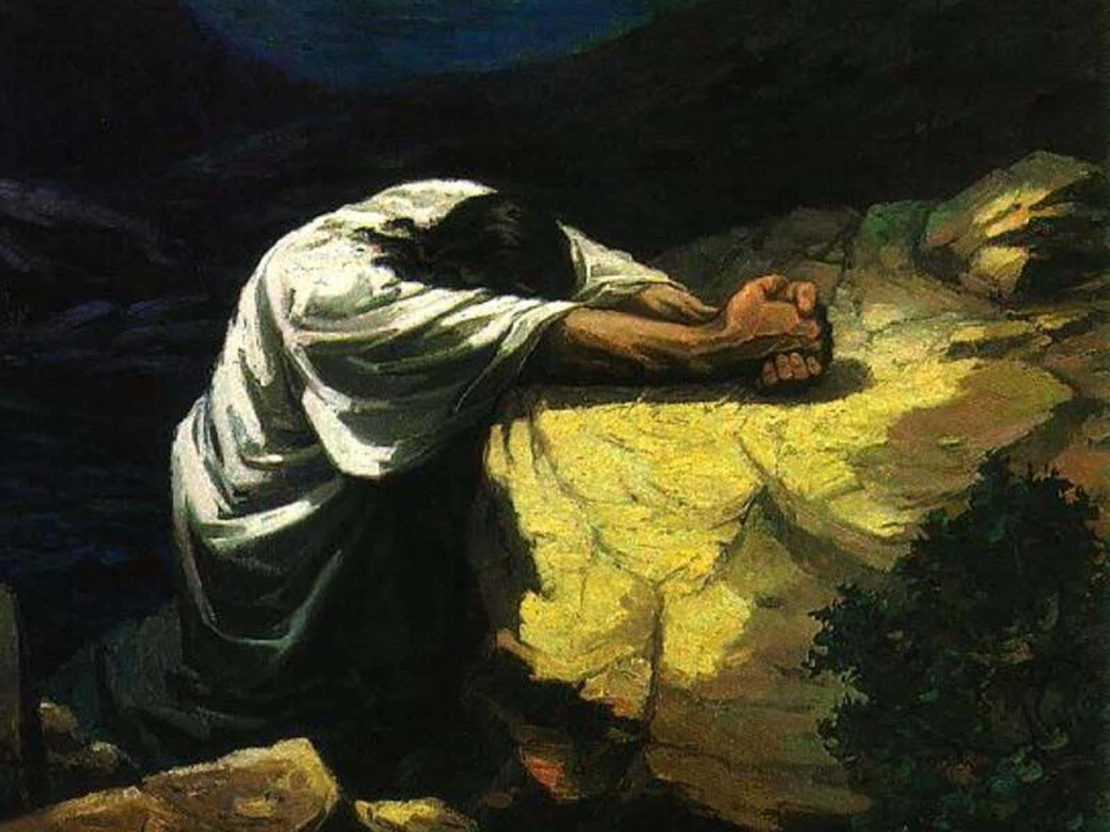 Praying 桌布 壁紙 — 一個身穿白衣的人影在夜晚的陽光照射的岩石上跪下祈禱，背後有黑暗的山脈和深藍色的天空。