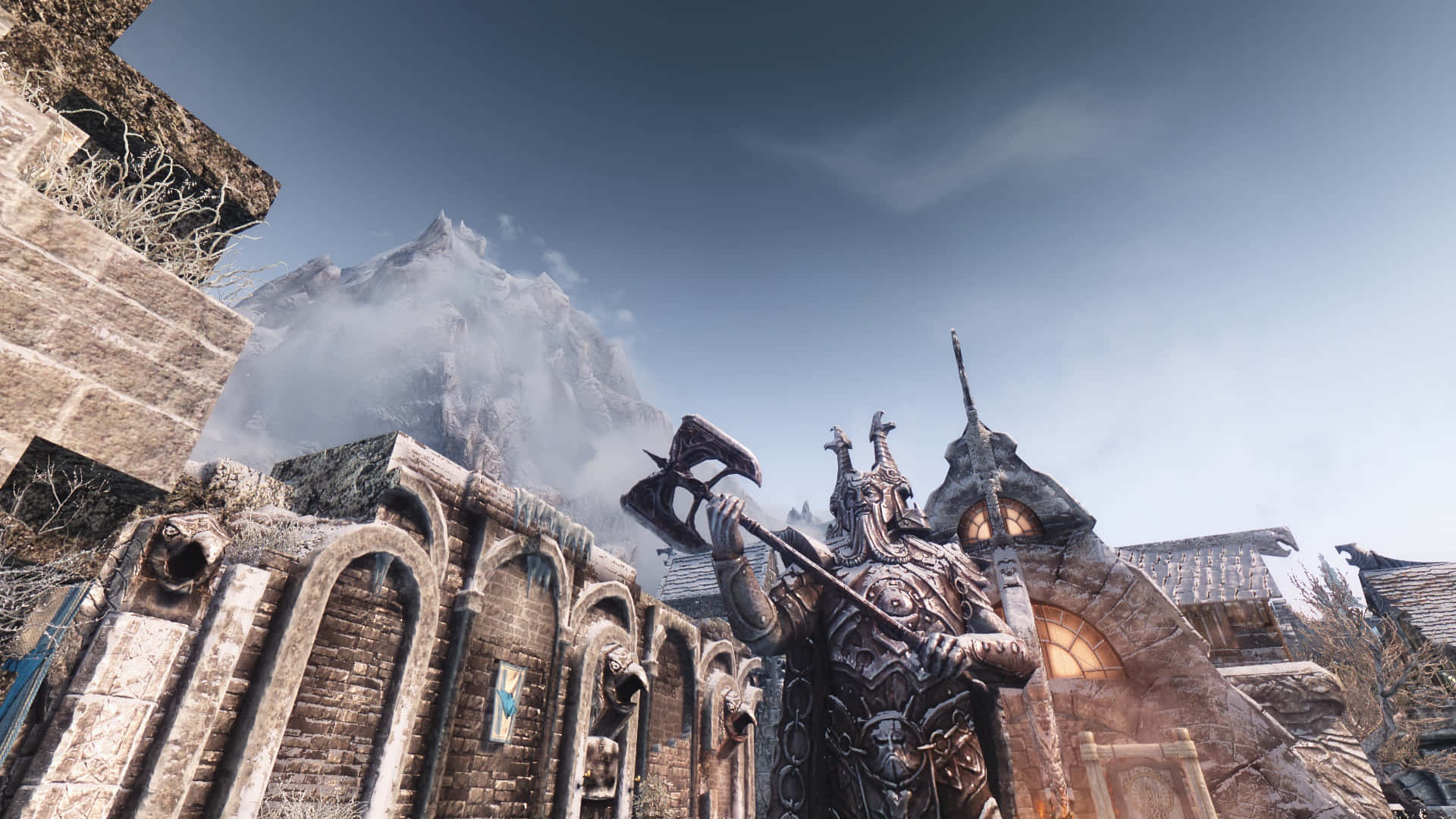 Skyrim Windhelm 桌布 壁紙 — 一個身穿盔甲、手持巨斧的高大戰士，站在多雲天空下的古老石廢墟前，背景是白雪覆蓋的山峰。