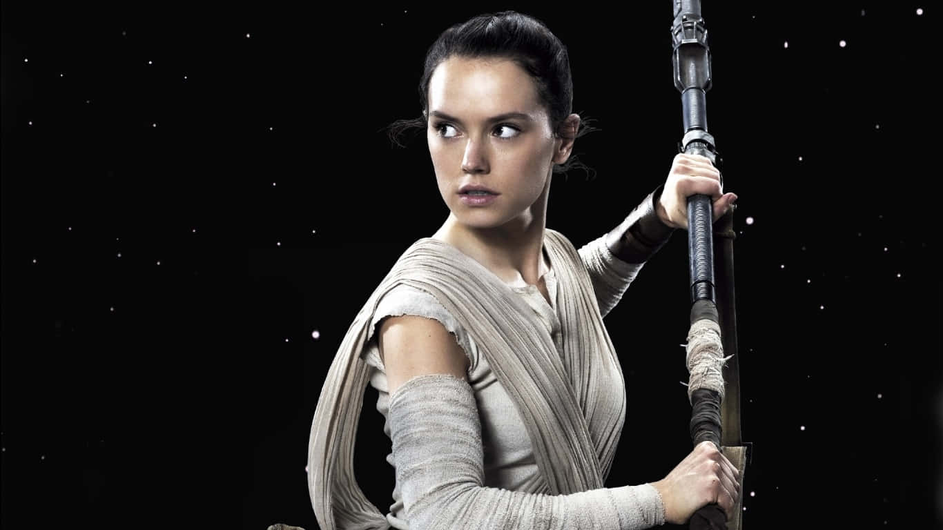Rey Star Wars 桌布 壁紙 — 一個身穿破爛米色長袍的堅定女子，在佈滿星光的黑色虛空中緊握著法杖，雙眼堅定地向前凝視。