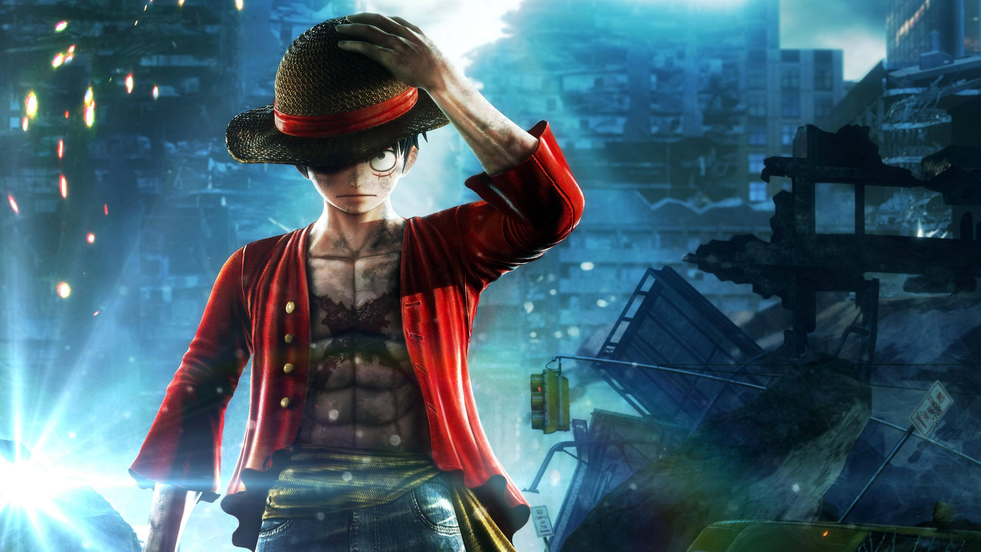 luffy 4K 桌布 壁紙 — 一個身穿紅色外套、戴著草帽的年輕海盜，在明亮的藍天下， defiantly 站在廢墟般的城市景觀中。
