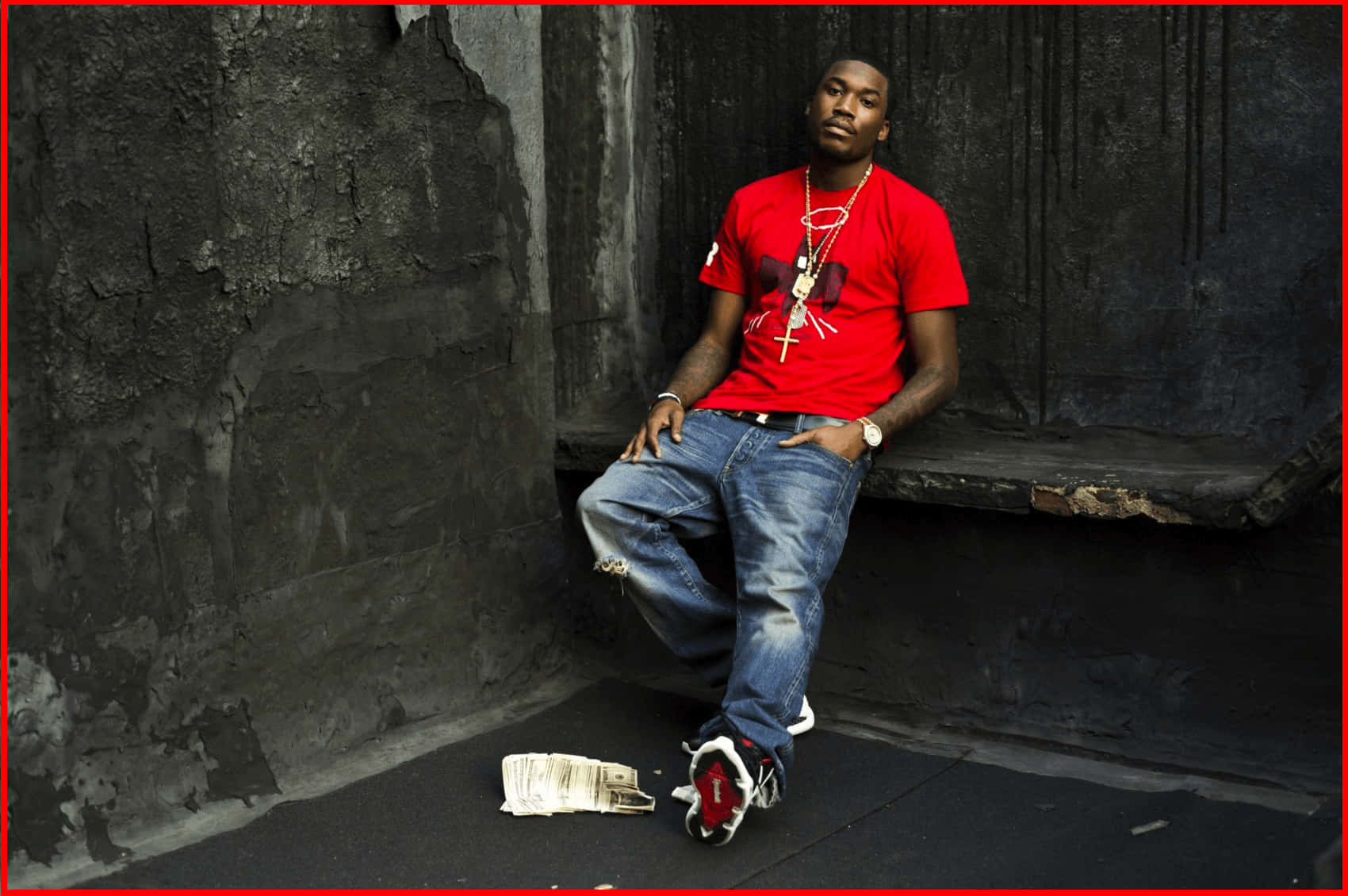 Meek 桌布 壁紙 — 一個身穿紅色襯衫和牛仔褲的男人靠在一面風化的混凝土牆上，腳邊有一張皺巴巴的報紙。
