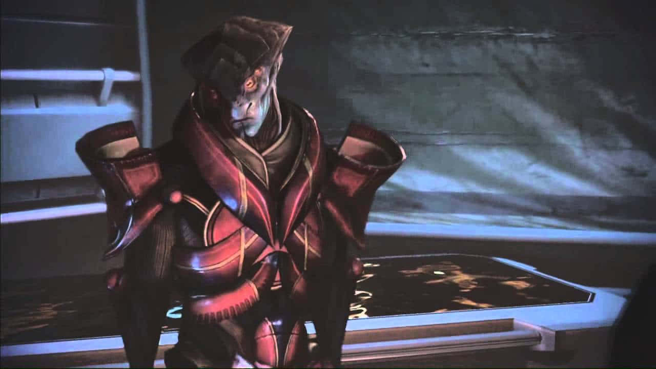 Mass Effect Javik 桌布 壁紙 — 一個身穿紅黑盔甲的威脅性外星戰士站在一個昏暗的未來房間中，房間內有發光的藍色面板。