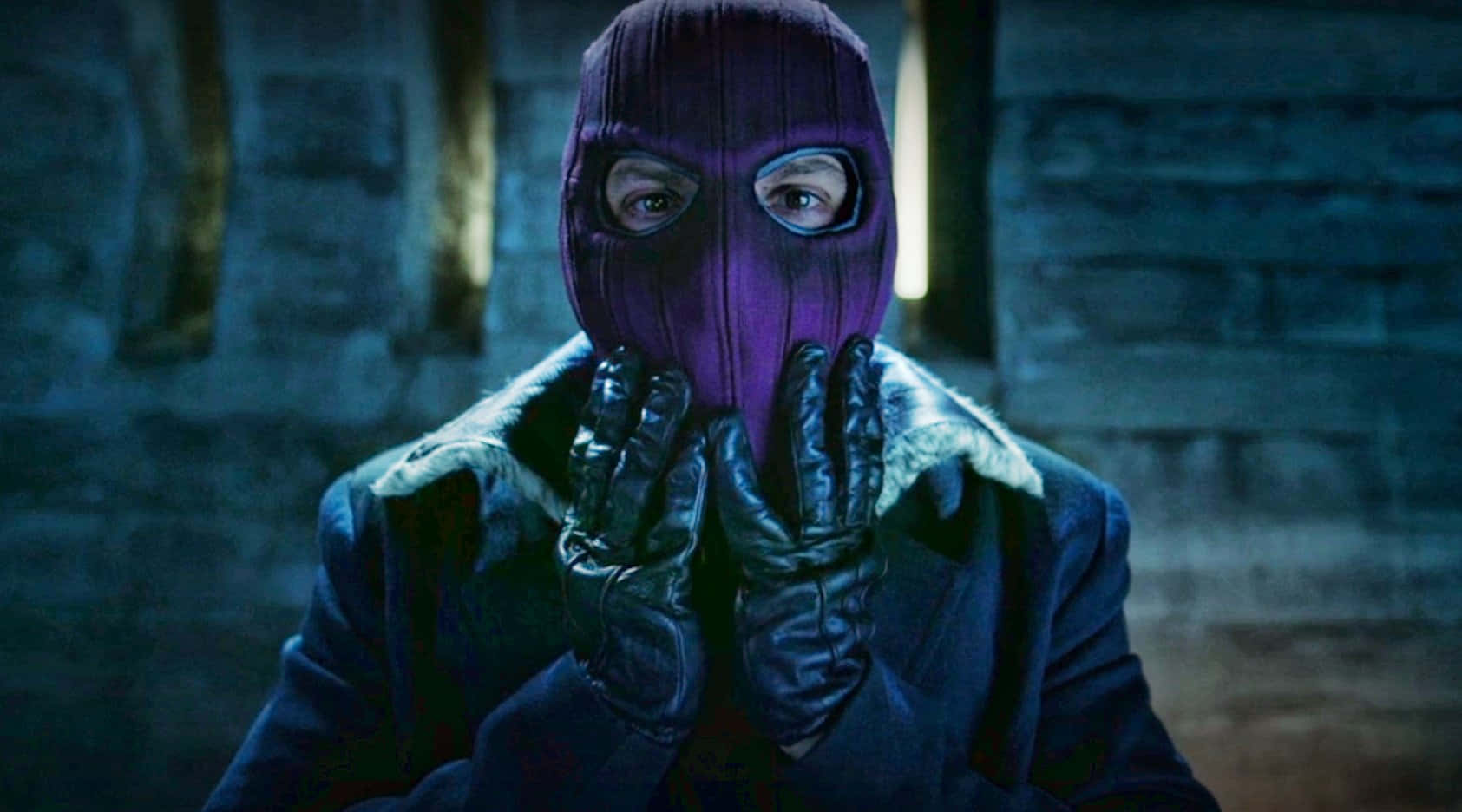 Baron Zemo 桌布 壁紙 — 一個身穿紫色巴拉克拉法帽和皮手套的人物，在光線昏暗的石頭走廊中將手放在臉上。