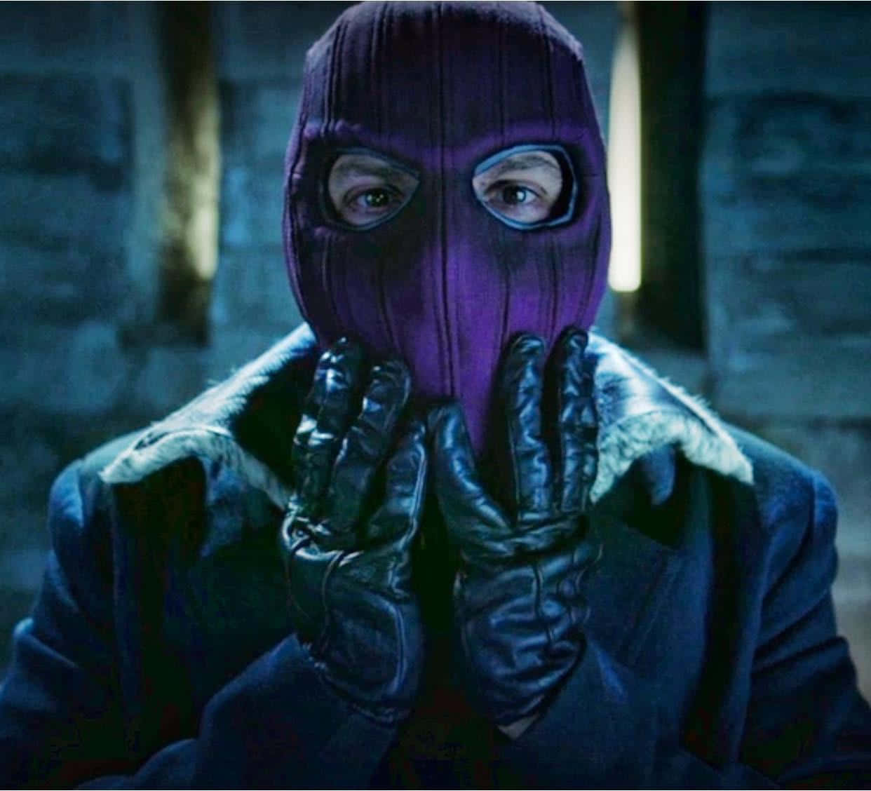 Baron Zemo 桌布 壁紙 — 一個身穿紫色巴拉克拉法帽和黑色手套的人物，在昏暗的石頭走廊中將雙手靠近臉部。