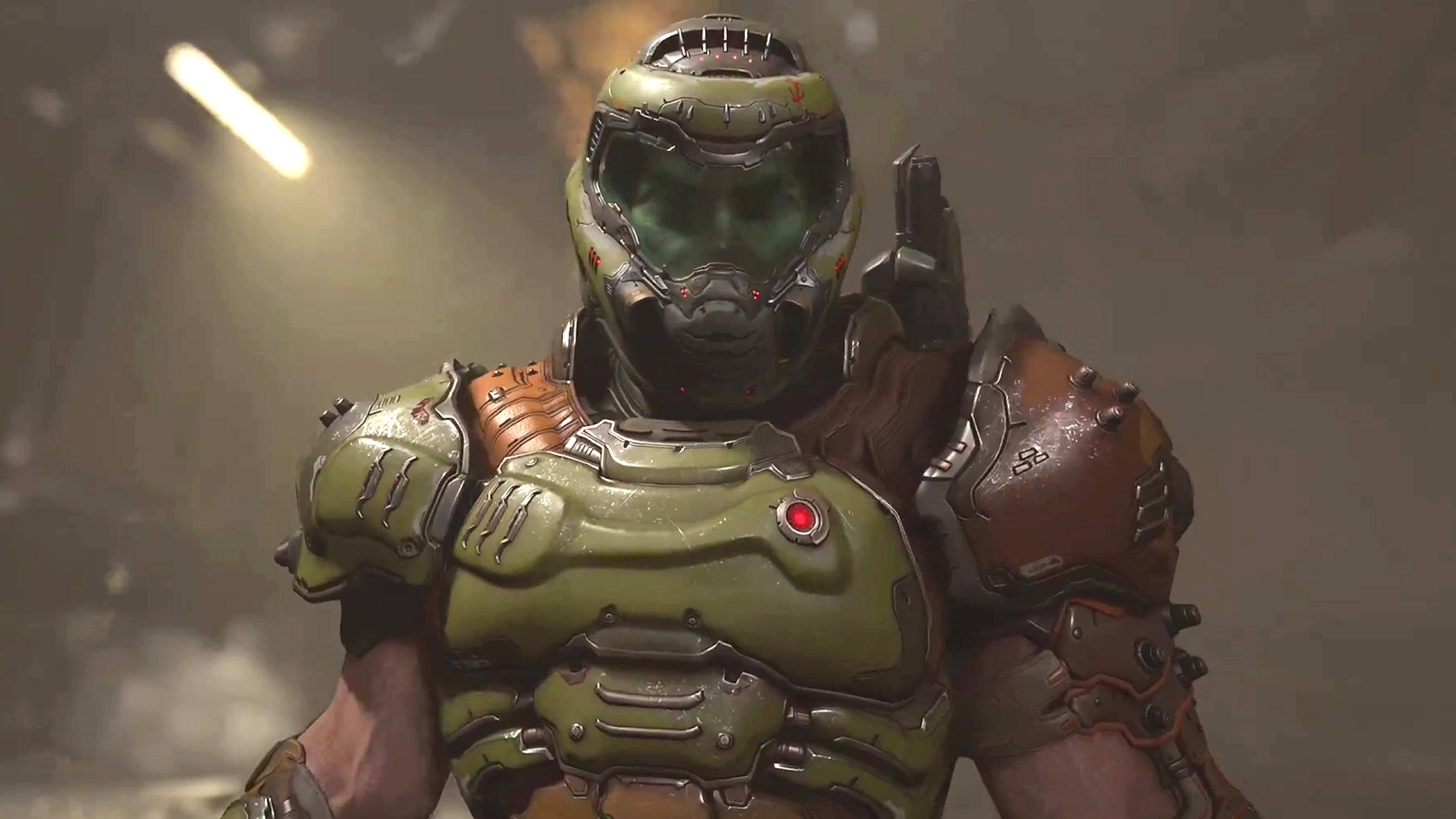 Doomguy 桌布 壁紙 — 一個身穿綠色和棕色動力裝甲的威脅性裝甲戰士，站在光線昏暗的工業環境中，上方有發光的燈光。
