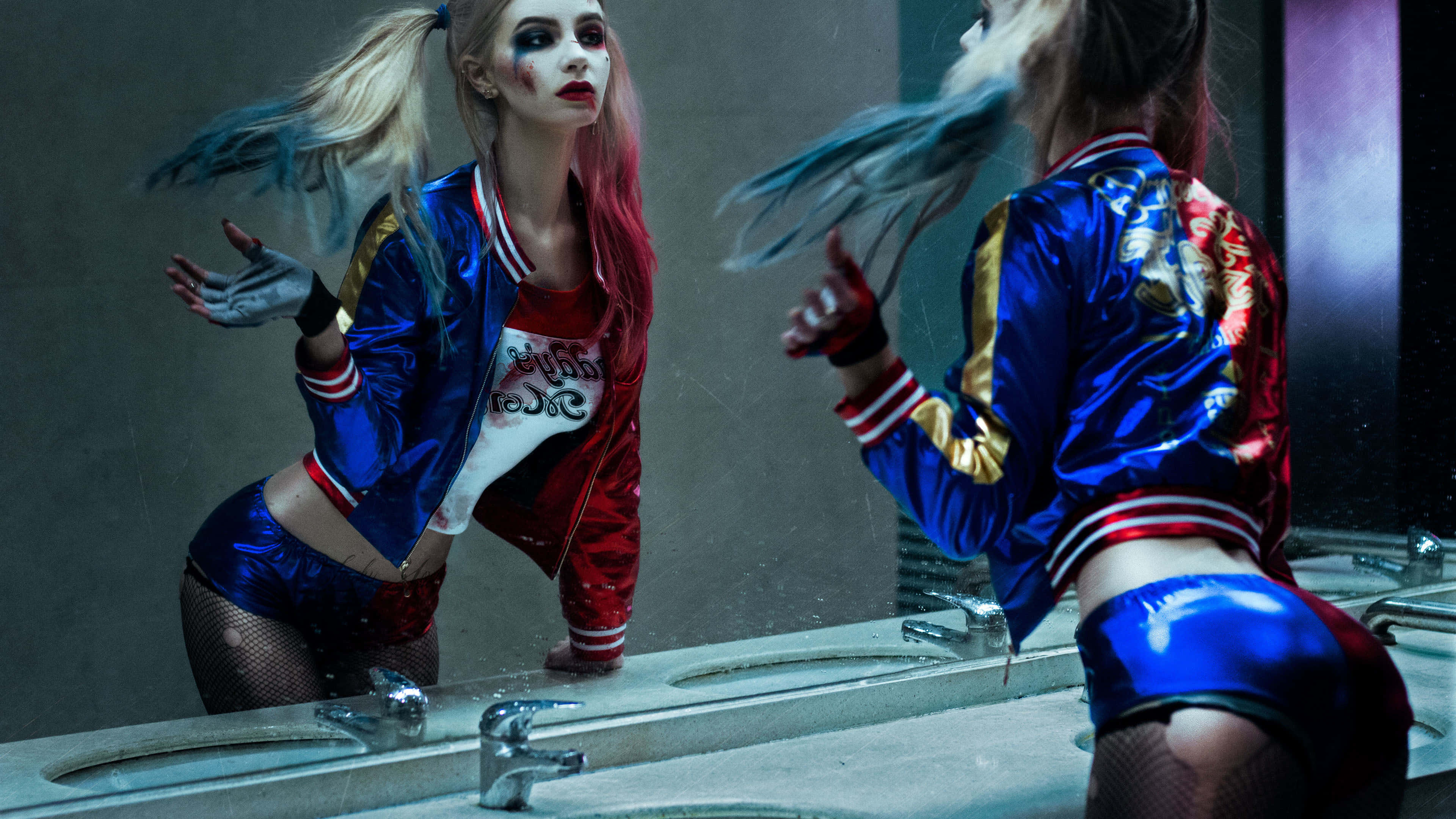 Harley Quinn Cosplay 桌布 壁紙 — 一個身穿藍紅外套、頭髮凌亂的女人俯身在水槽上，她的倒影映在濕漉漉的浴室鏡子中。