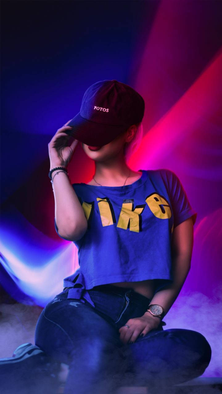 phone girl 桌布 壁紙 — 一個身穿藍色Nike短版上衣和帽子的人坐在充滿活力的紫色和粉紅色霓虹燈光中，煙霧在他們周圍繚繞。