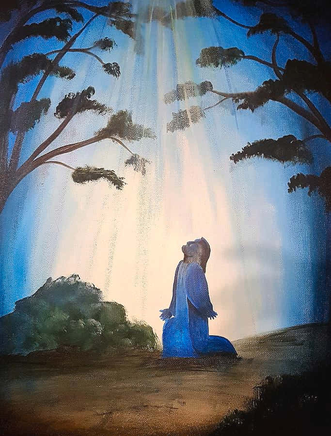 Jesus Praying 桌布 壁紙 — 一個身穿藍色的人物跪在神聖光線下，光線穿過黑暗樹木，映照在寧靜的森林場景中。