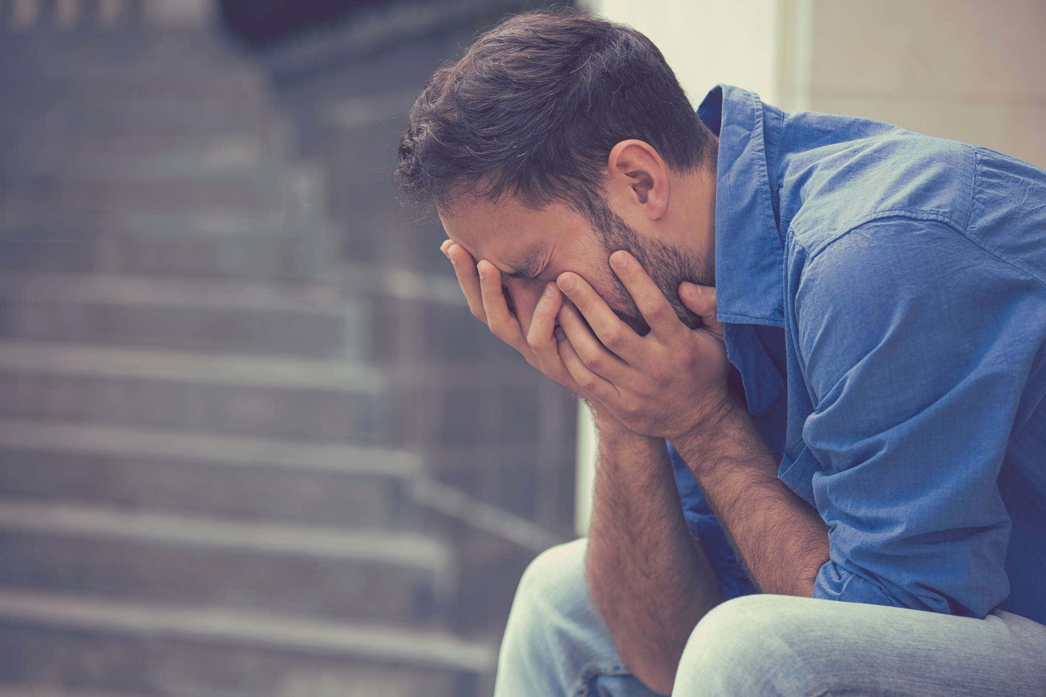 Stress 桌布 壁紙 — 一個身穿藍色襯衫的男人坐在石階上，雙手遮住臉龐，看起來似乎很痛苦或疲憊。