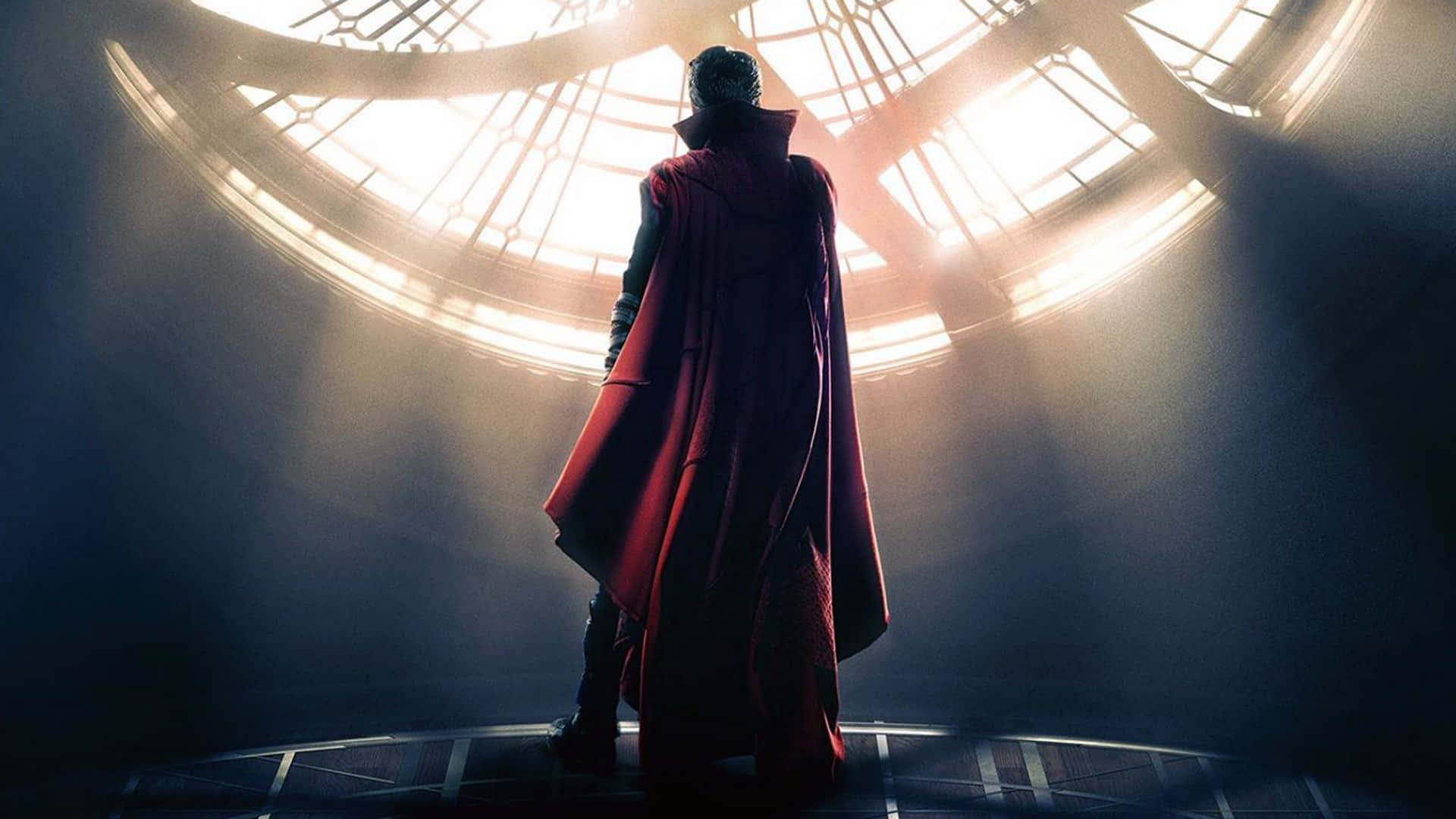 Dr Strange 桌布 壁紙 — 一個身穿飄逸紅色斗篷的身影，在發光的圓形天窗下以剪影呈現，戲劇性的光束穿過霧氣瀰漫的空氣。