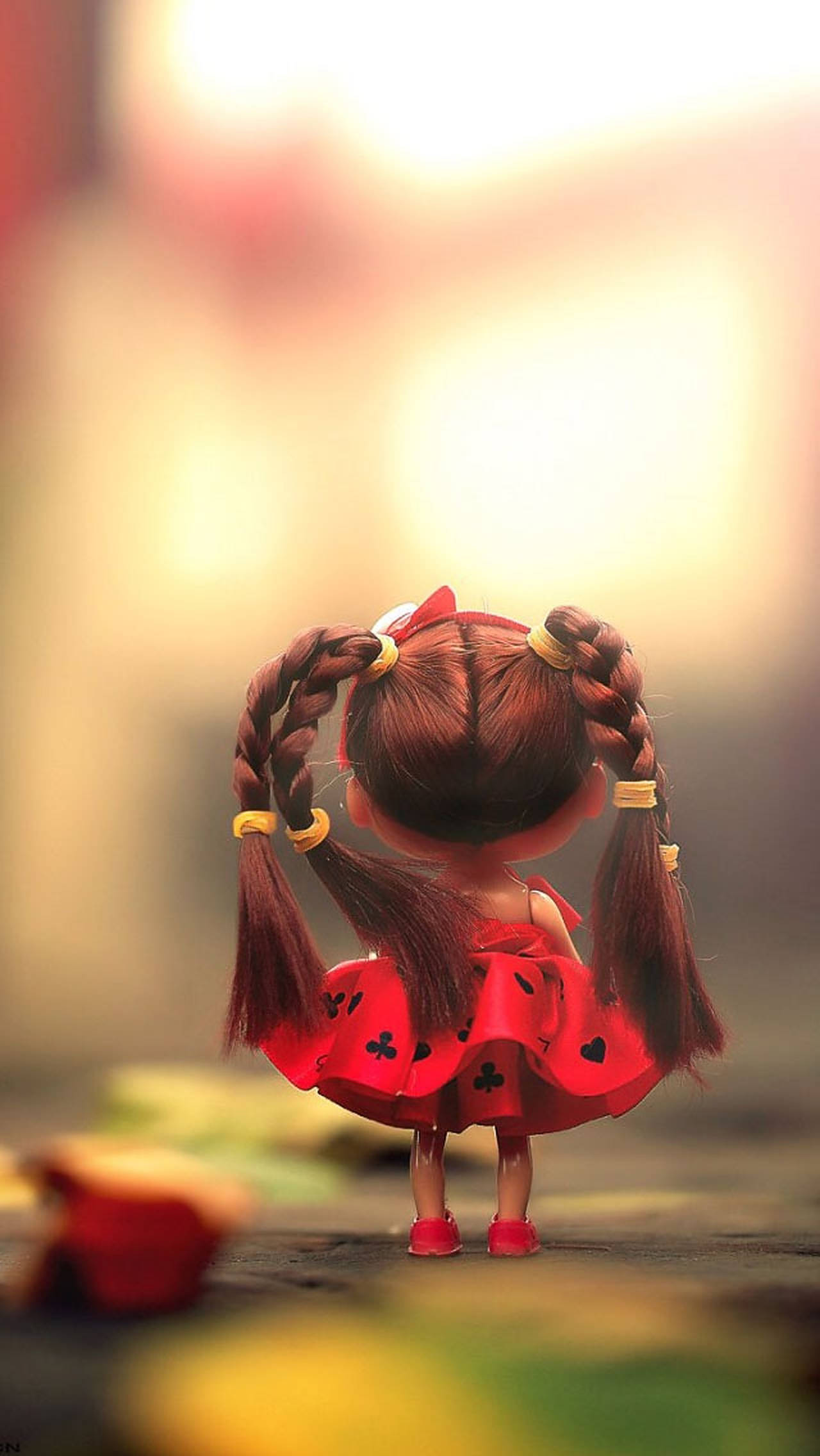 Doll 桌布 壁紙 — 一個辮子棕色頭髮、穿著紅色連衣裙的洋娃娃背對著觀眾，背景溫暖而模糊。
