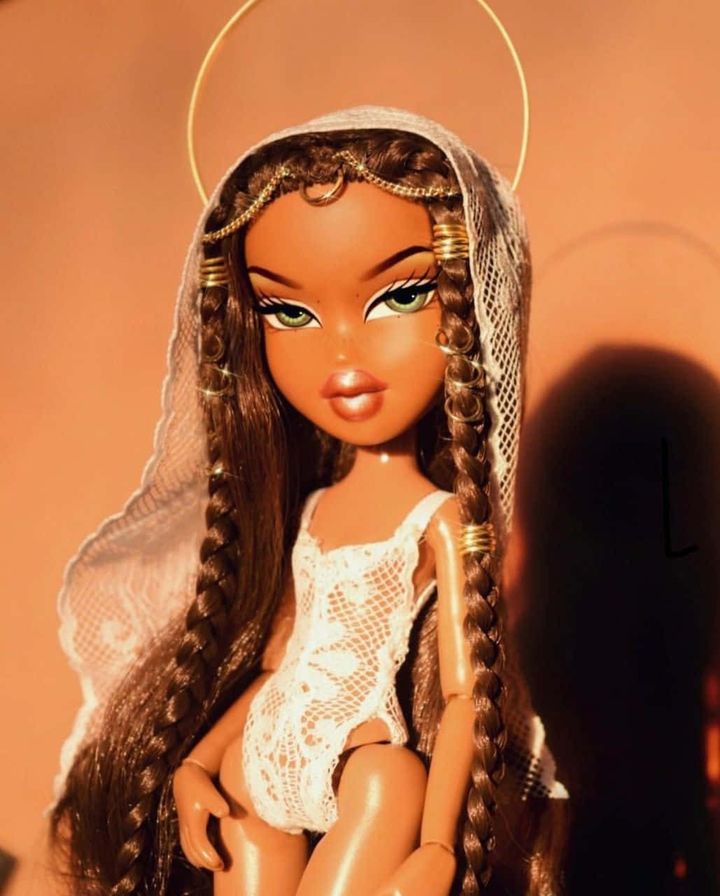 Bratz 桌布 壁紙 — 一個辮子頭髮、帶有光環的玩偶，在溫暖的橙色背景下穿著白色蕾絲連體衣。