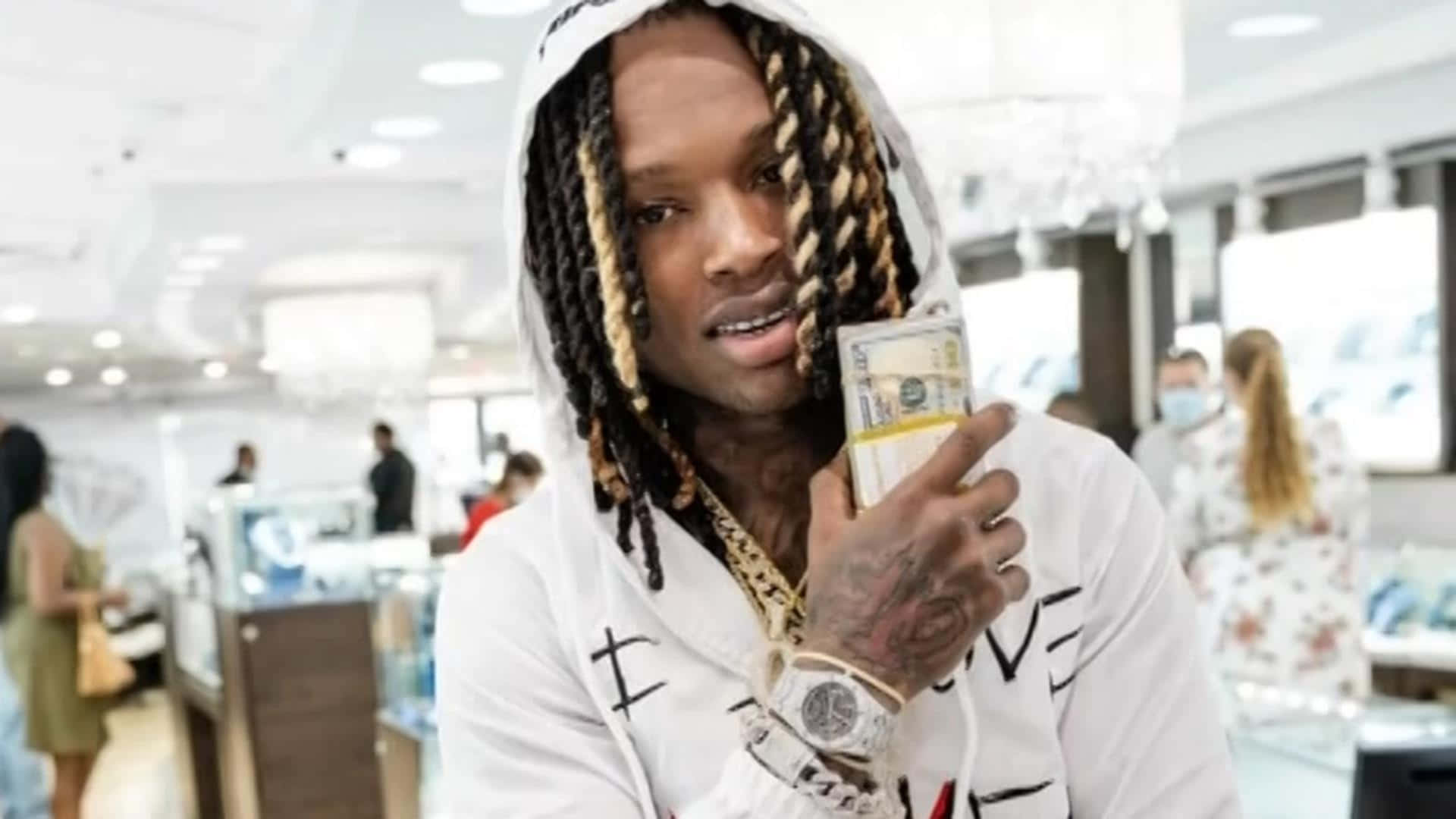 男人在珠寶店裡拿著現金，穿著連帽衫和金錶。 — King Von 壁紙