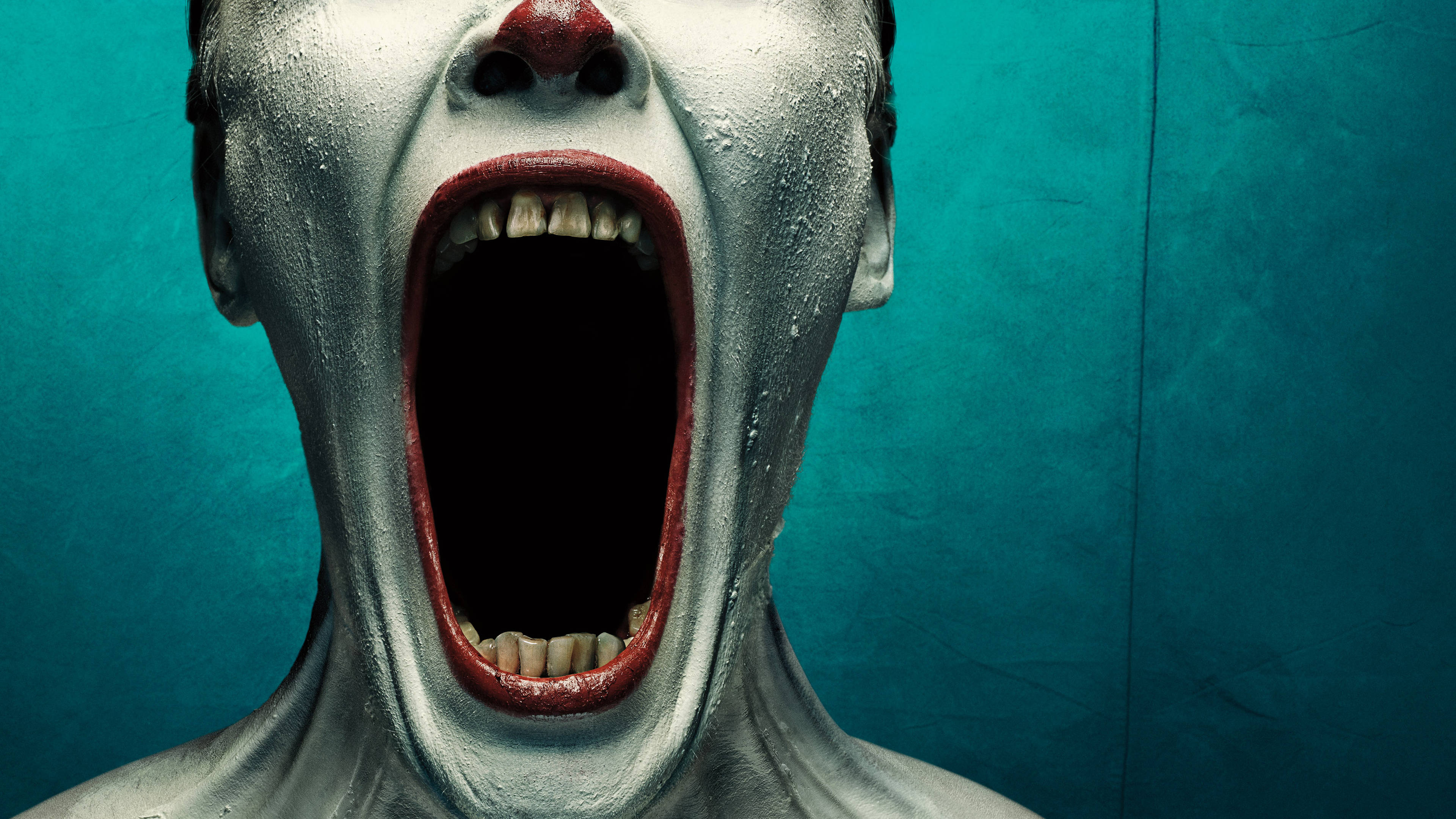 American Horror Story 桌布 壁紙 — 一個近距離拍攝，一個人臉上塗著白色顏料，紅唇，對著藍綠色紋理背景尖叫。