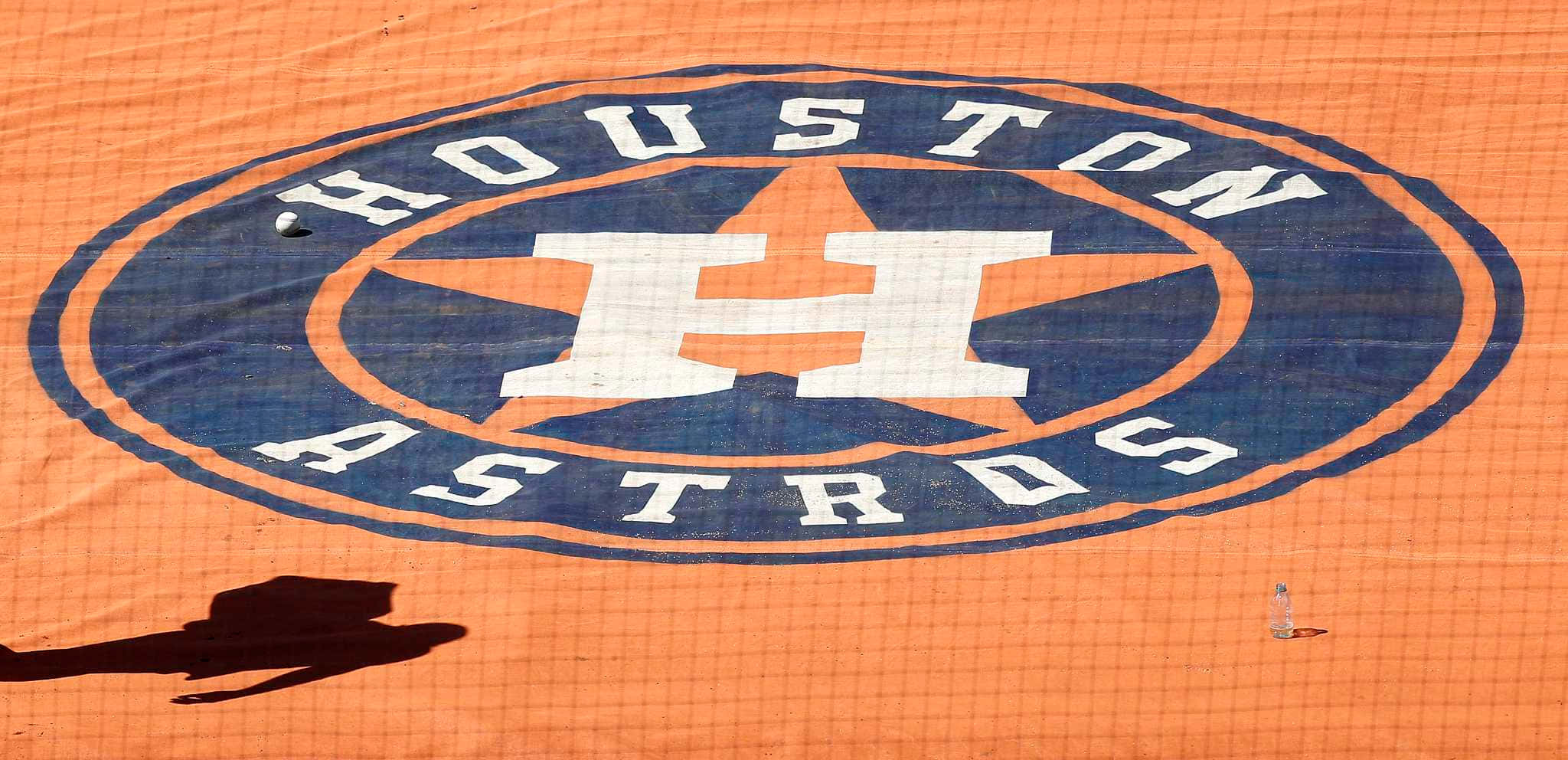 Astros 桌布 壁紙 — 一個近距離拍攝的休士頓太空人標誌，繪在橙色網狀表面上，並有人的影子投射在上面。
