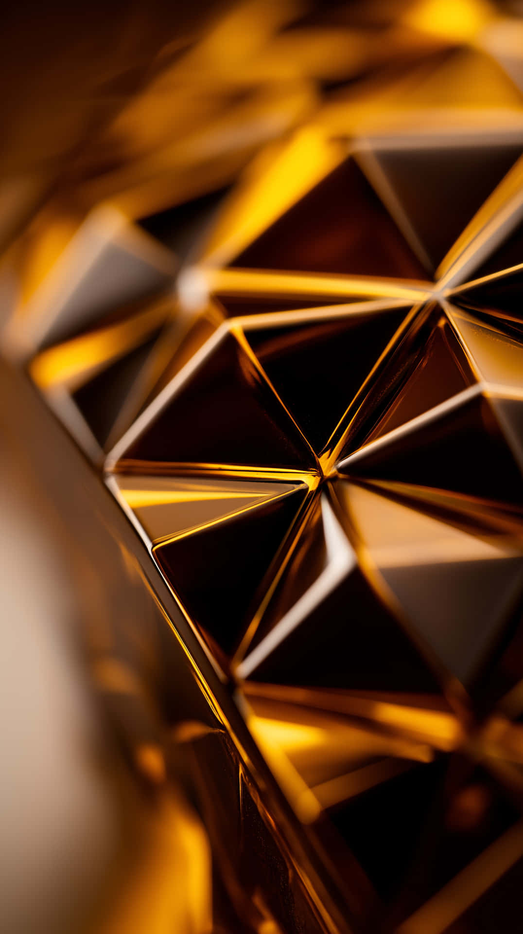 Golden Abstract Facets 壁紙 — 一個近距離拍攝的切割金色幾何表面，帶有銳利的三角形平面，反射溫暖光線。