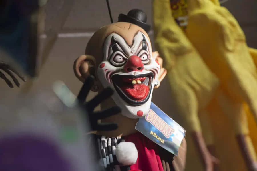 Creepy Clown 桌布 壁紙 — 一個近距離拍攝的怪誕小丑面具，有大眼睛、紅鼻子和鋸齒狀的笑容，掛著作為萬聖節裝飾。