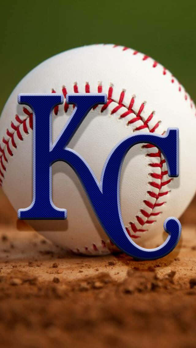 Kc Royals 桌布 壁紙 — 一個近距離拍攝的棒球，上面有醒目的藍色KC標誌，放在棕色泥土上，背景為綠色。