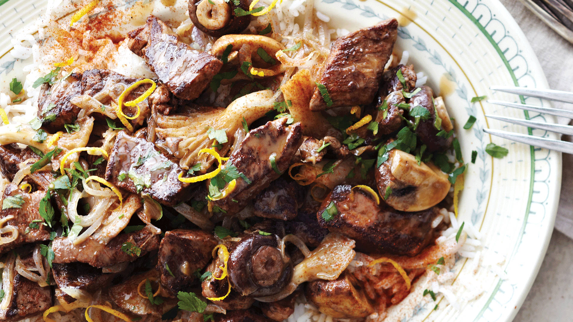Beef Stroganoff 桌布 壁紙 — 一個近距離拍攝的鹹味菜餚，有煎肉、蘑菇、洋蔥和檸檬皮碎，放在白飯上，用一個有圖案的盤子盛裝。