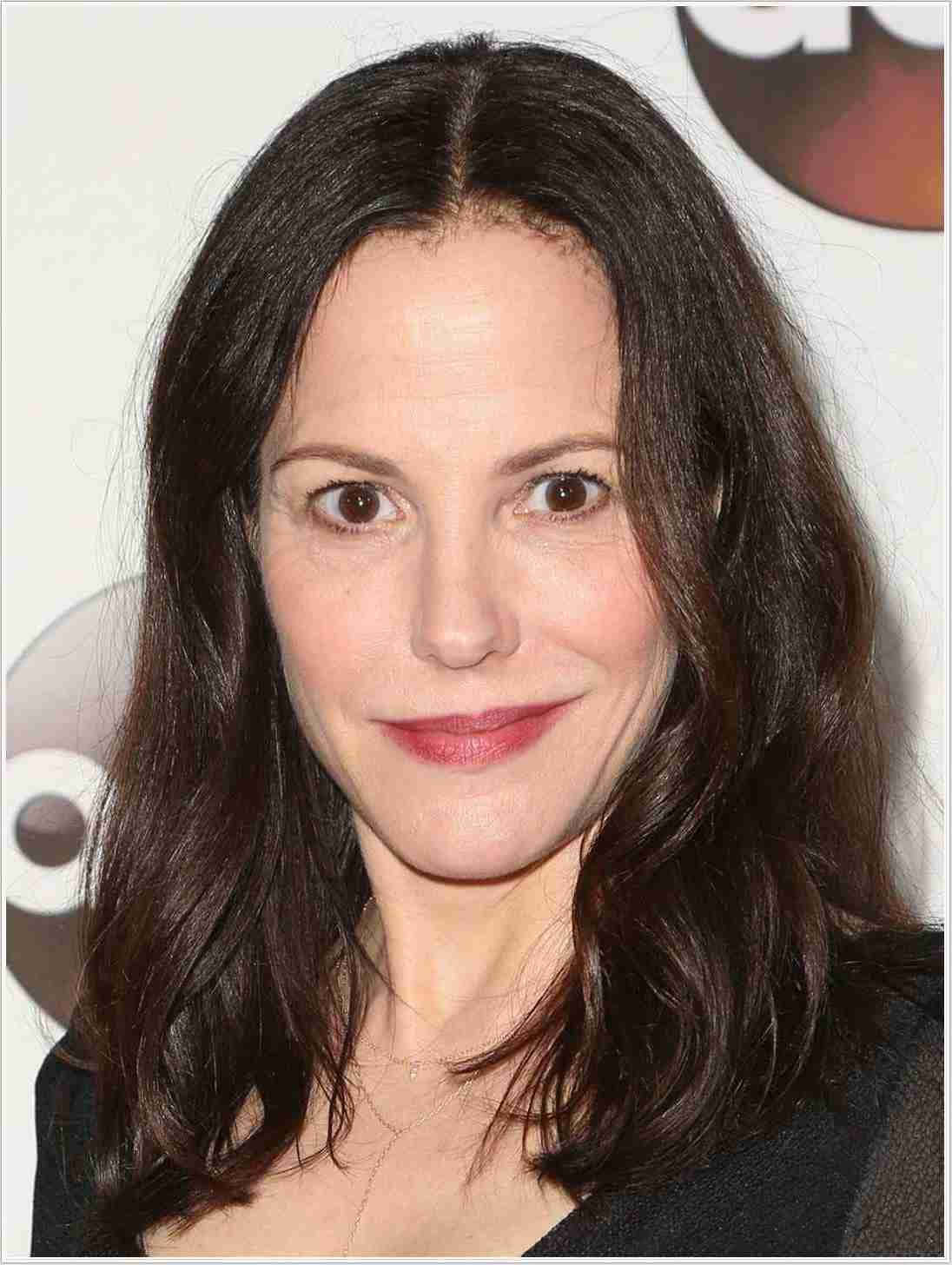 mary louise parker 桌布 壁紙 — 一個近距離肖像，一位深色波浪髮的女性，在模糊的活動背景下露出溫柔的微笑。
