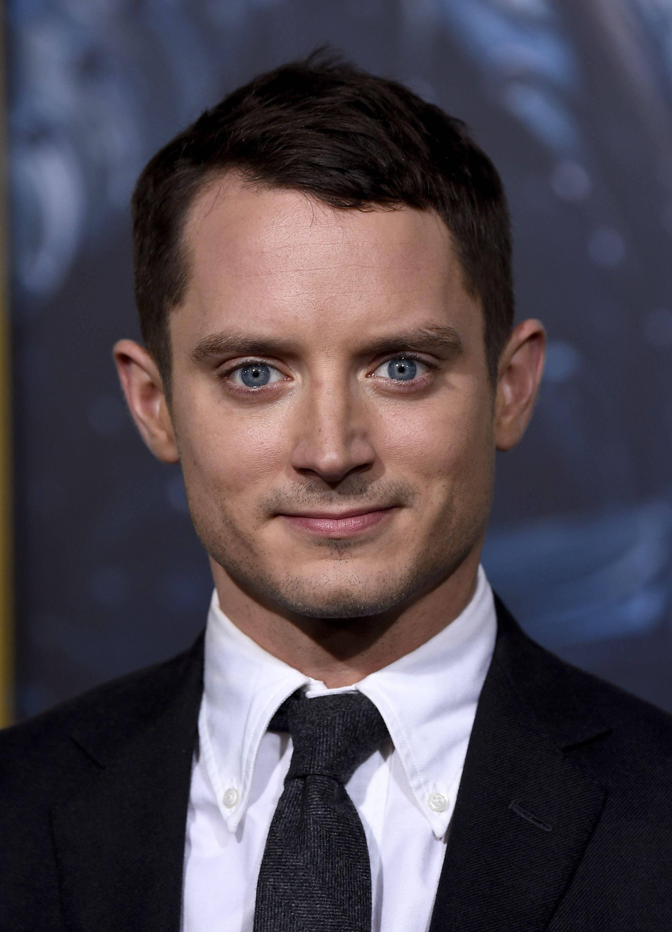 Celebrity 桌布 壁紙 — 一個近距離肖像，一個男人擁有引人注目的藍眼睛，穿著黑色西裝和領帶，背景是模糊的藍色。