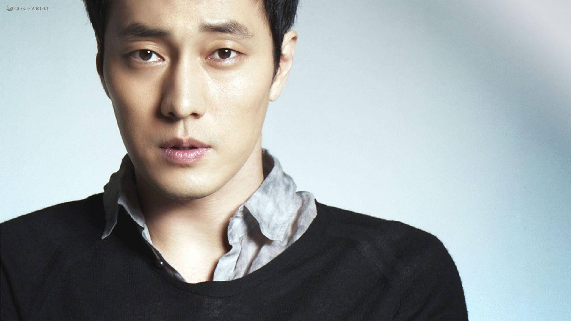 Actors 桌布 壁紙 — 一個近距離肖像，一個眼神強烈的男人，穿著黑色毛衣內搭灰色襯衫，背景是柔和的藍色。