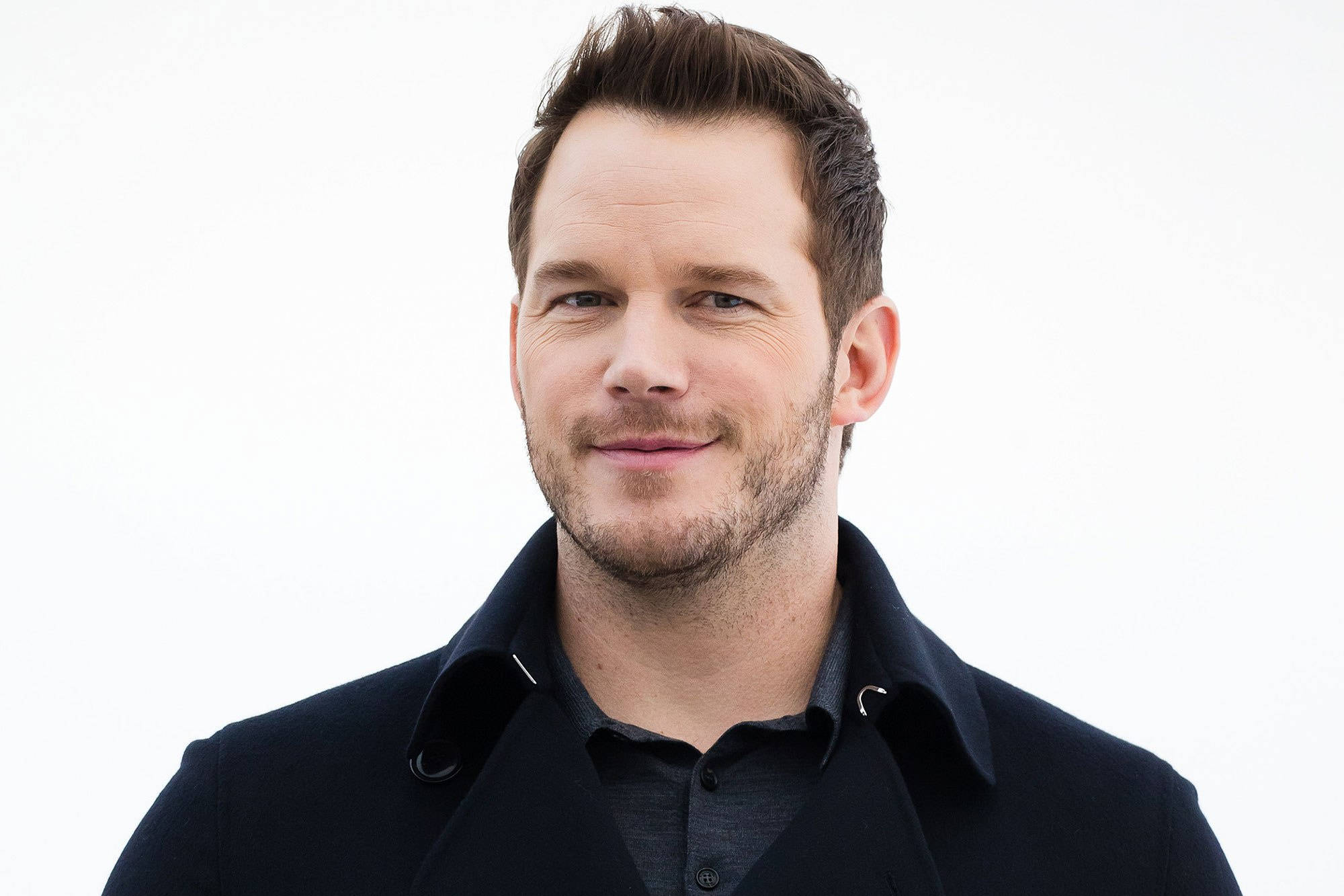 Chris Pratt 桌布 壁紙 — 一個近距離肖像，一個短棕髮、留著淺鬍鬚的男人，穿著深色外套，背景是純白色。
