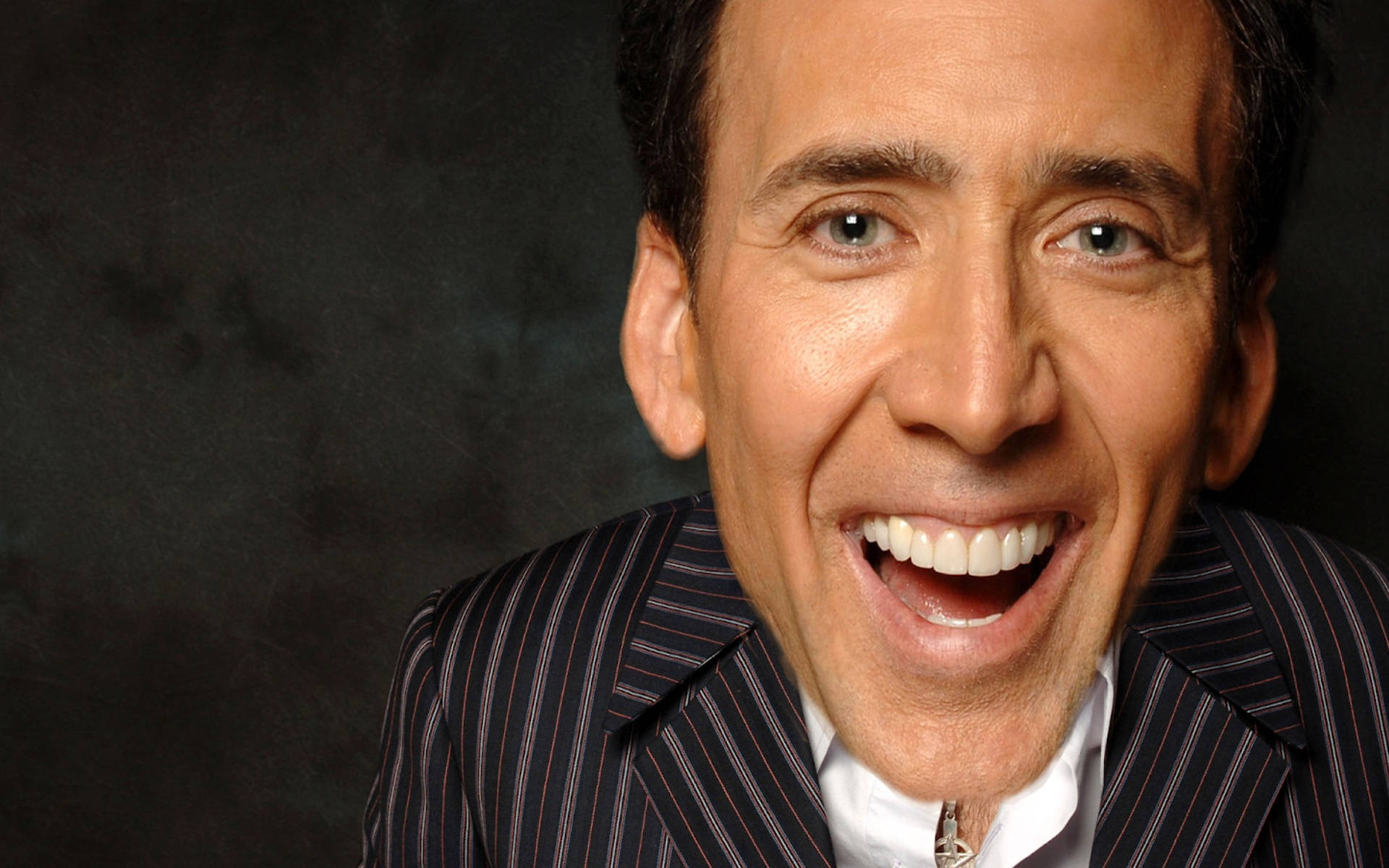 nicolas cage meme 桌布 壁紙 — 一個近距離肖像，一個穿著細條紋西裝的男人在黑暗紋理背景下爆發出寬廣歡樂的笑聲。