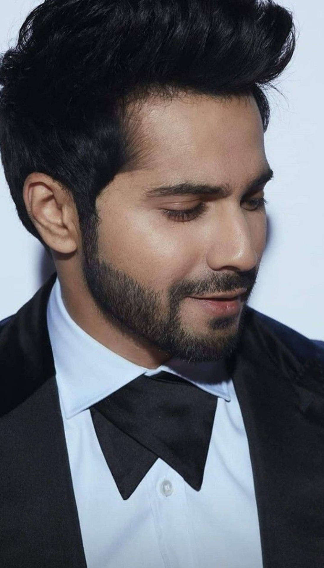 Varun 桌布 壁紙 — 一個近距離肖像，一名深色頭髮和鬍鬚的男子穿著黑色燕尾服和領結，背景為淺色。