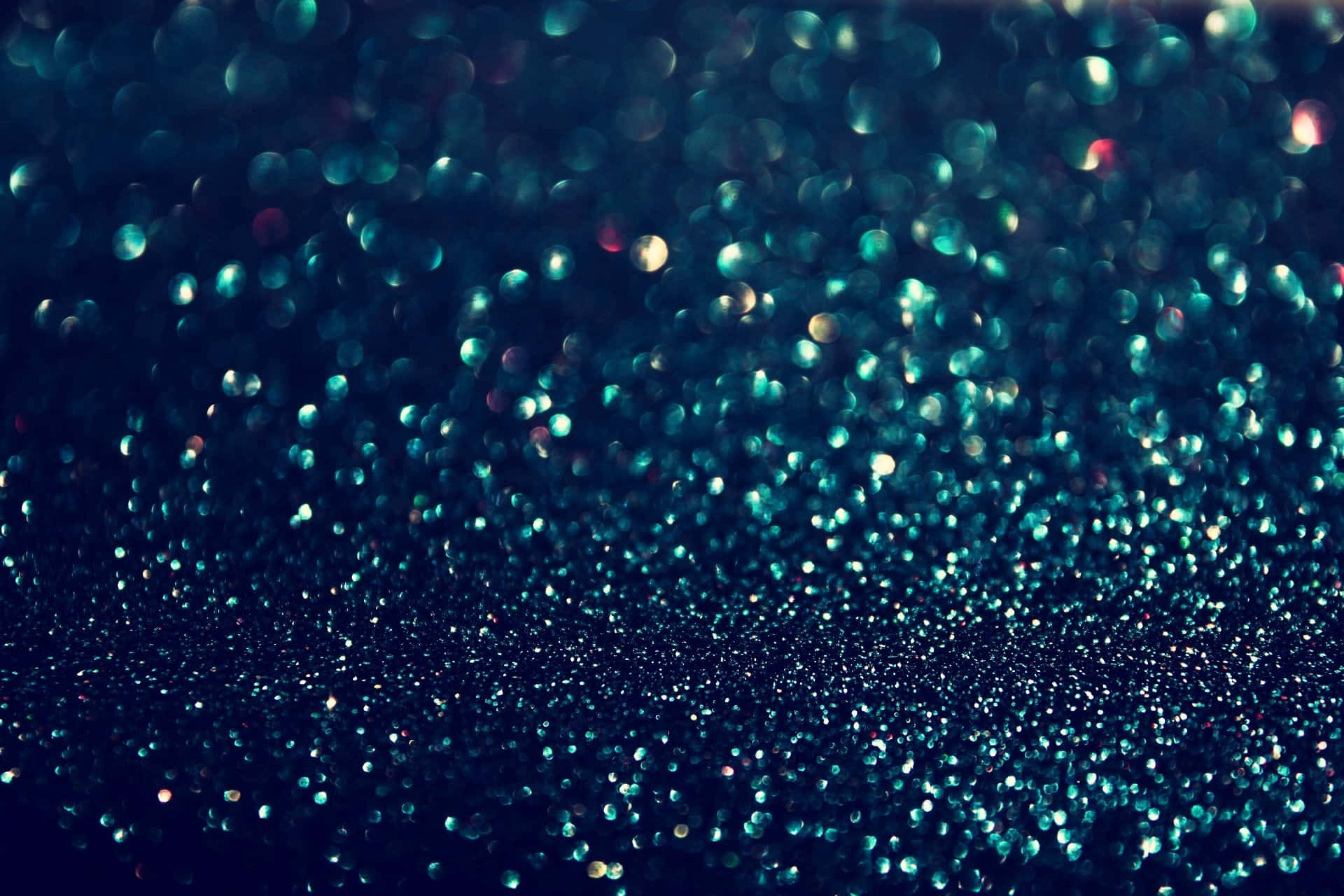 背景 桌布 壁紙 — 一個迷人的領域，由藍綠色和金色亮粉顆粒組成，在深藍色背景上柔和地模糊成夢幻般的散景。
