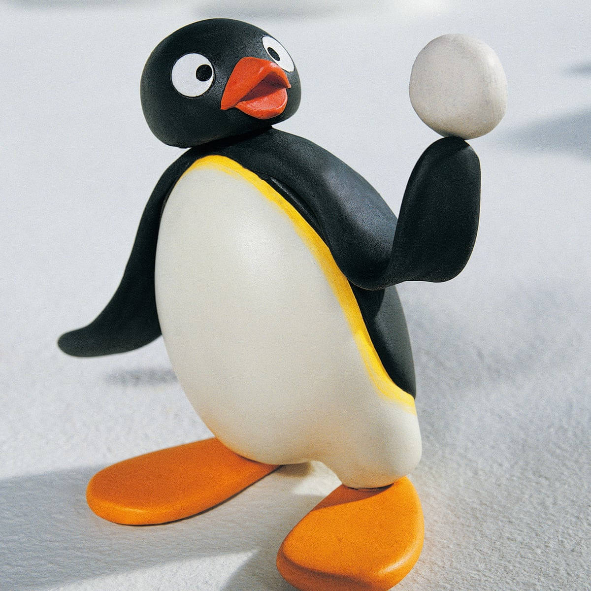 Pingu 桌布 壁紙 — 一個迷人的黏土企鵝公仔，有橙色喙和腳，在雪景背景下拿著雪球。