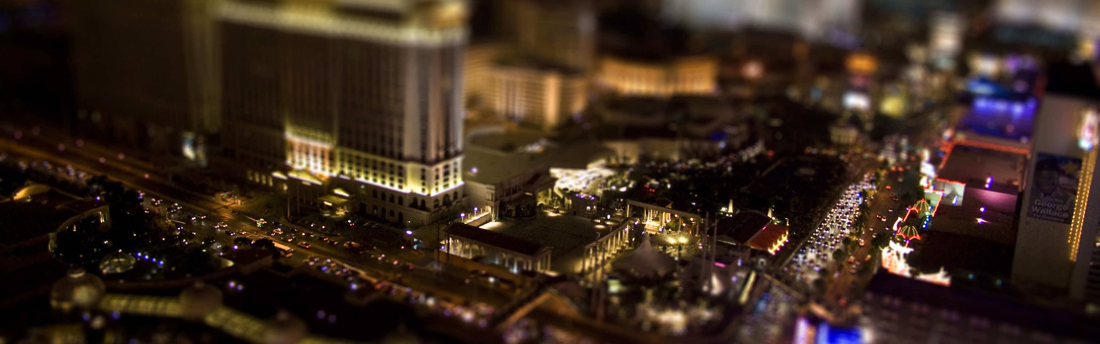 3D 桌布 壁紙 — 一個迷你風格的夜景城市景觀，在溫暖的人造燈光下，建築物發光，街道繁忙。