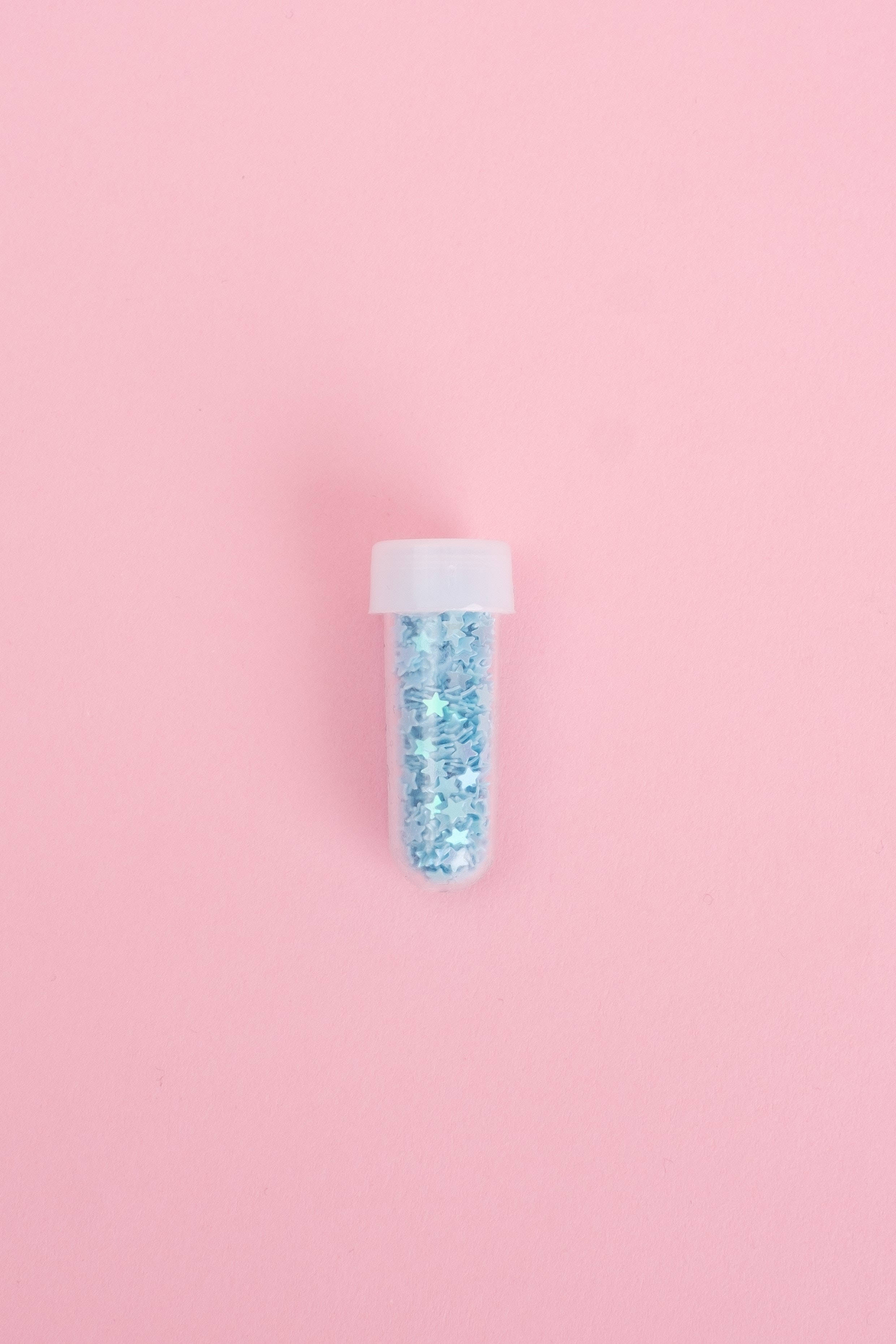 Pink And Blue 桌布 壁紙 — 一個透明塑膠管裝滿藍色亮粉，置於柔和粉紅色背景中央。