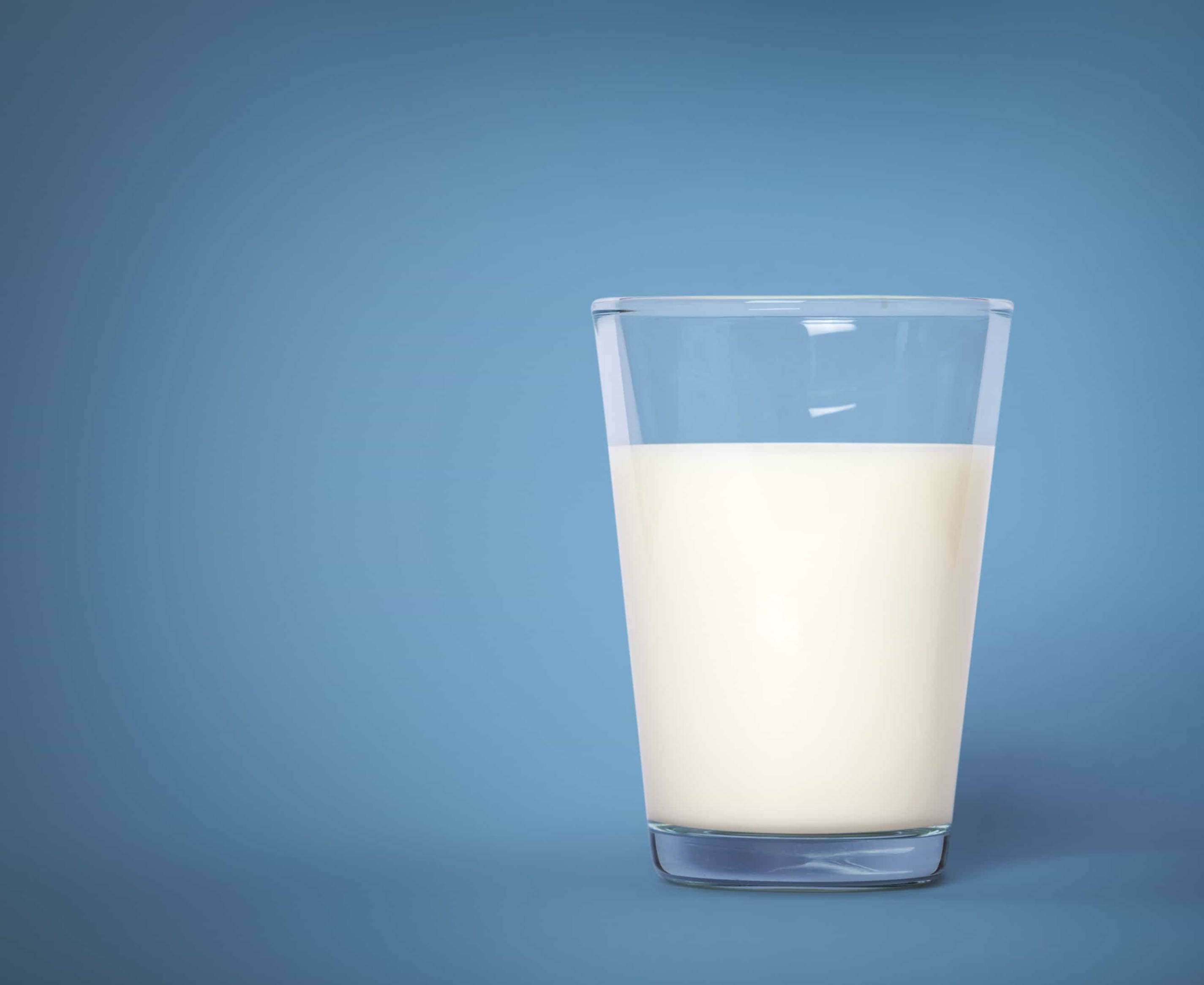Milk 桌布 壁紙 — 一個透明玻璃杯半滿著奶油狀的白色牛奶，置於平滑漸變藍色背景的中央。