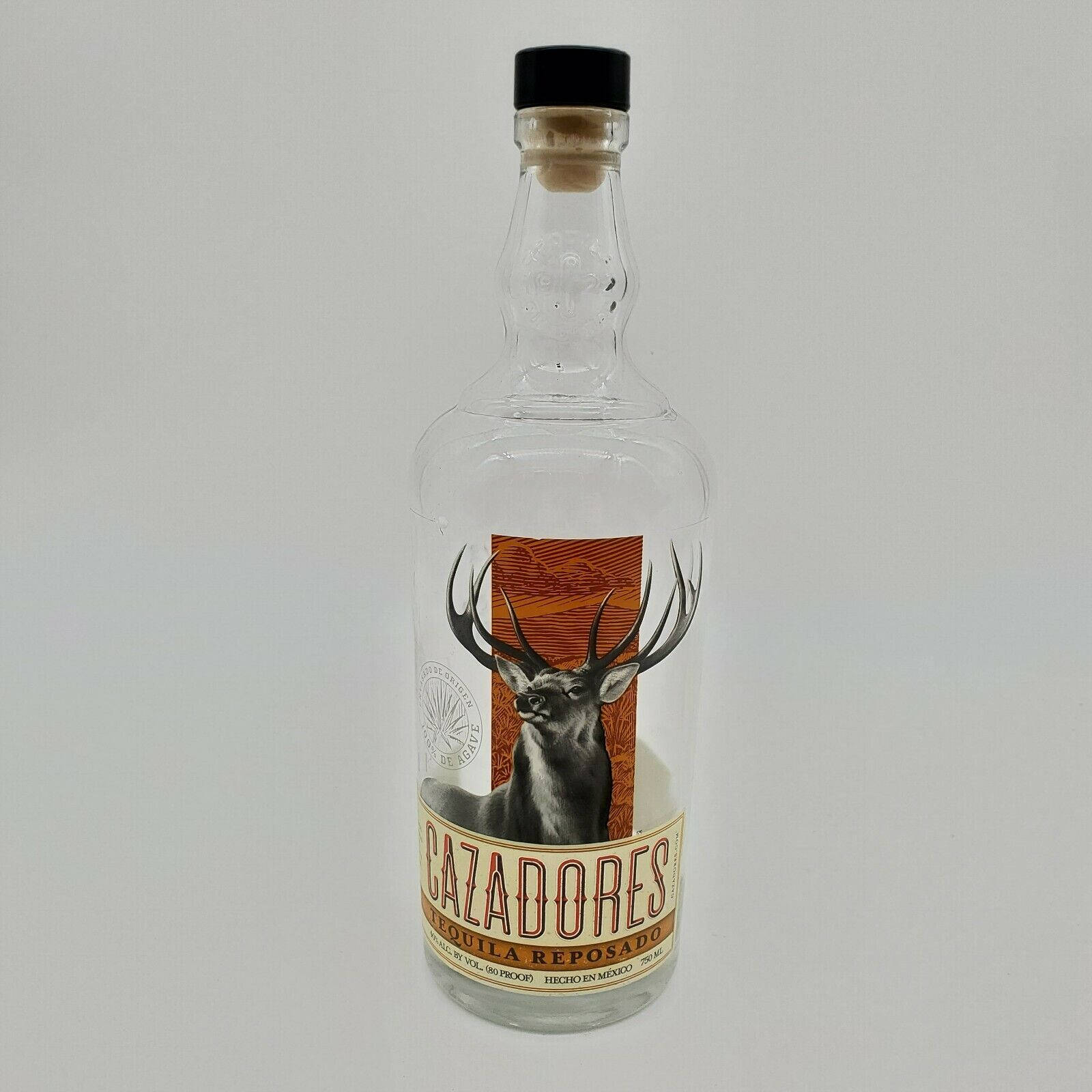 alcohol 桌布 壁紙 — 一個透明玻璃瓶的Cazadores Reposado龍舌蘭酒，標籤上有鹿的插圖，立在純白色背景前。