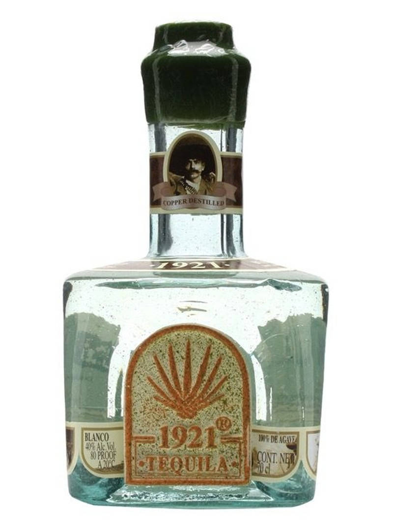 drinks 桌布 壁紙 — 一個透明玻璃瓶裝的1921 Blanco龍舌蘭酒，帶有綠色瓶蓋和復古標籤，上面有男士肖像和龍舌蘭植物。
