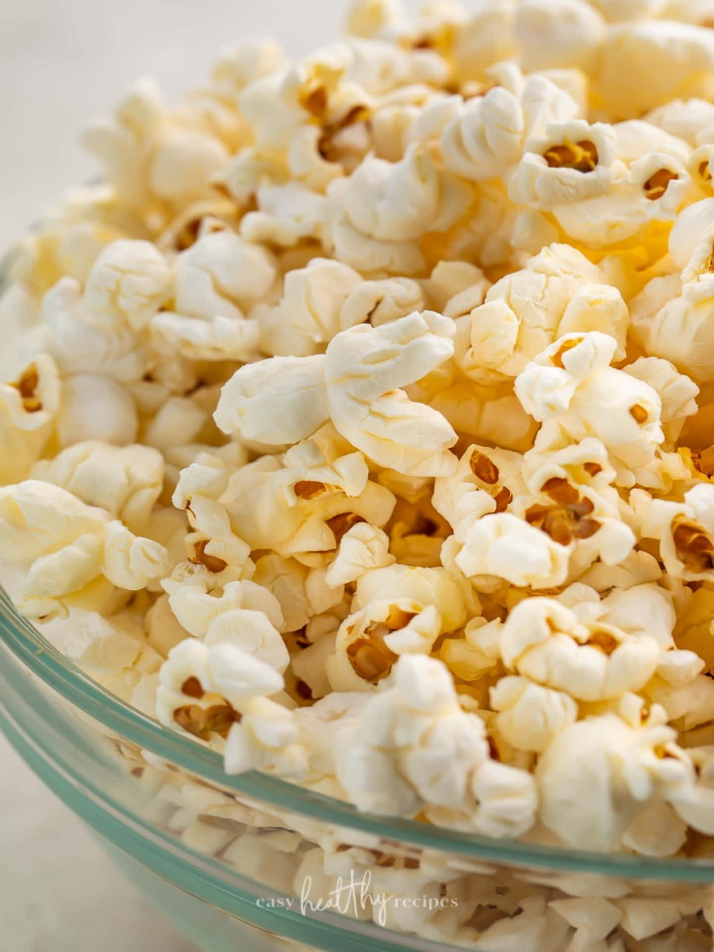 Popcorn 桌布 壁紙 — 一個透明玻璃碗中蓬鬆白色爆米花與金色穀粒的特寫。