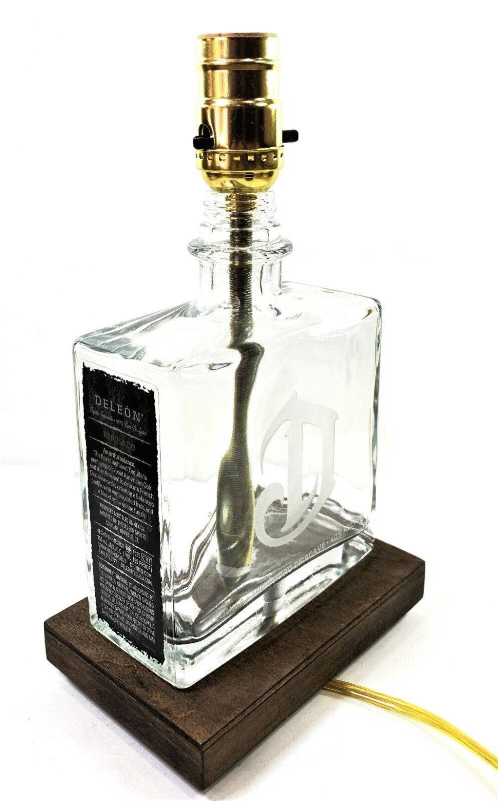 glass 桌布 壁紙 — 一個透明玻璃龍舌蘭酒瓶被重新用作燈具，配有金色燈座和木質底座。