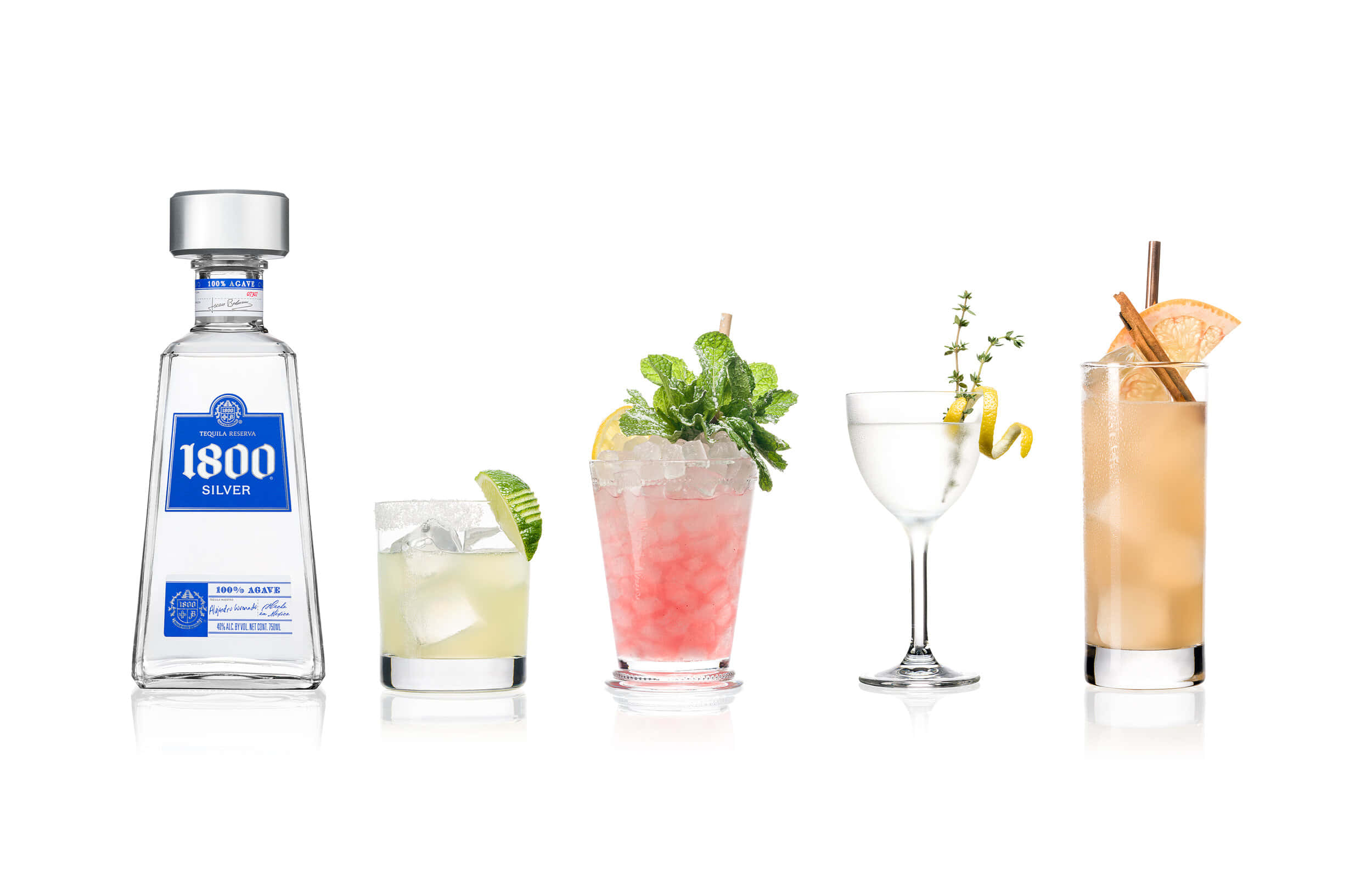 alcohol 桌布 壁紙 — 一個透明的1800 Silver龍舌蘭酒瓶旁邊放著四杯色彩繽紛的雞尾酒，飾以柑橘和香草，背景是純白色。