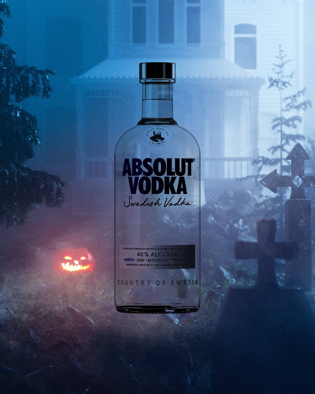 bottle 桌布 壁紙 — 一個透明的Absolut Vodka酒瓶矗立在霧氣瀰漫的墓地中，伴隨著發光的南瓜燈和哥德式建築，在詭異的藍光下。