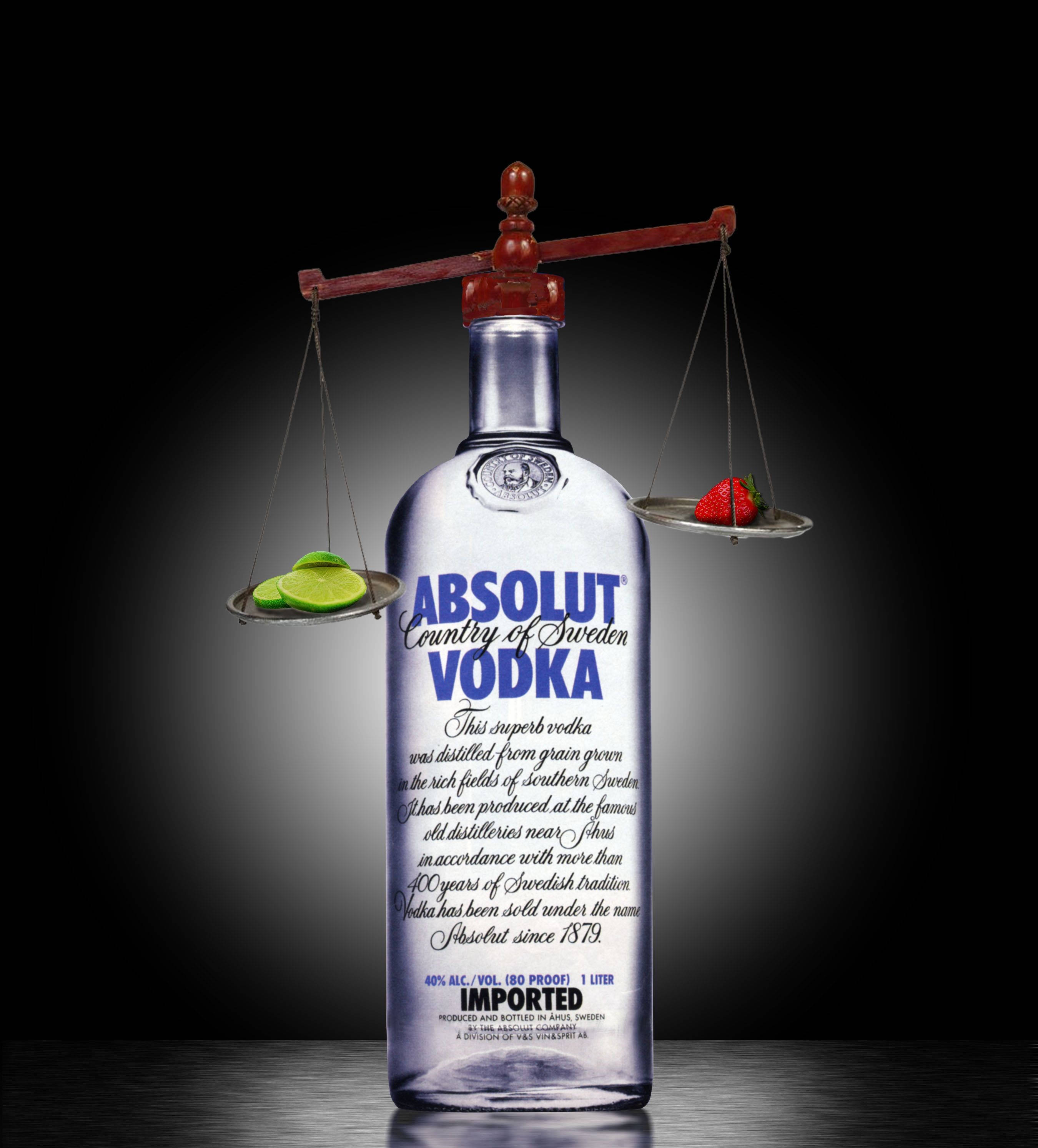 bottle 桌布 壁紙 — 一個透明的Absolut Vodka酒瓶在木秤上平衡一片萊姆和草莓，背景為深色漸層。