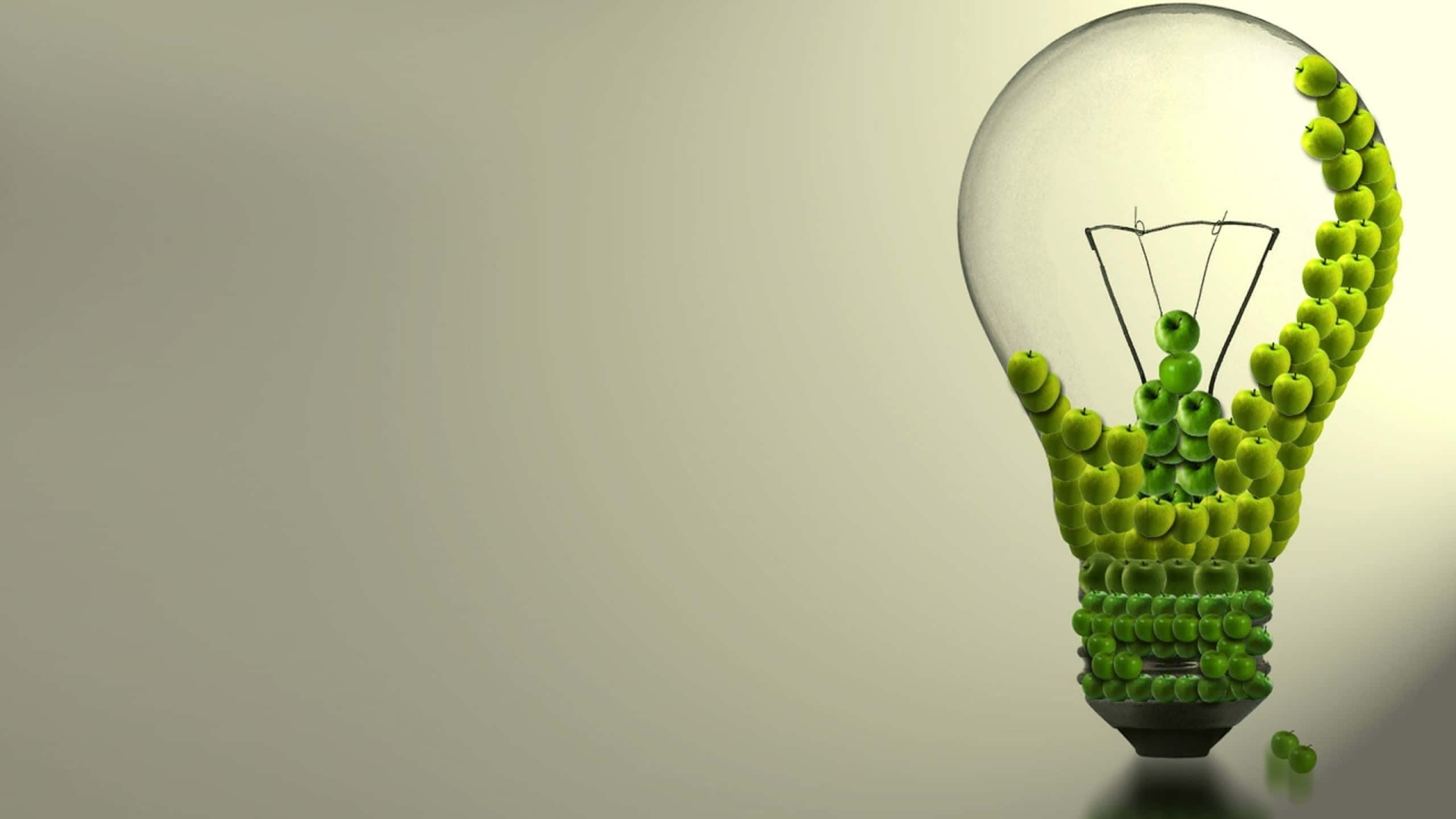 Light 桌布 壁紙 — 一個透明的燈泡，裡面裝滿了青蘋果，排列成發光的燈絲和底座，背景是柔和的米色。