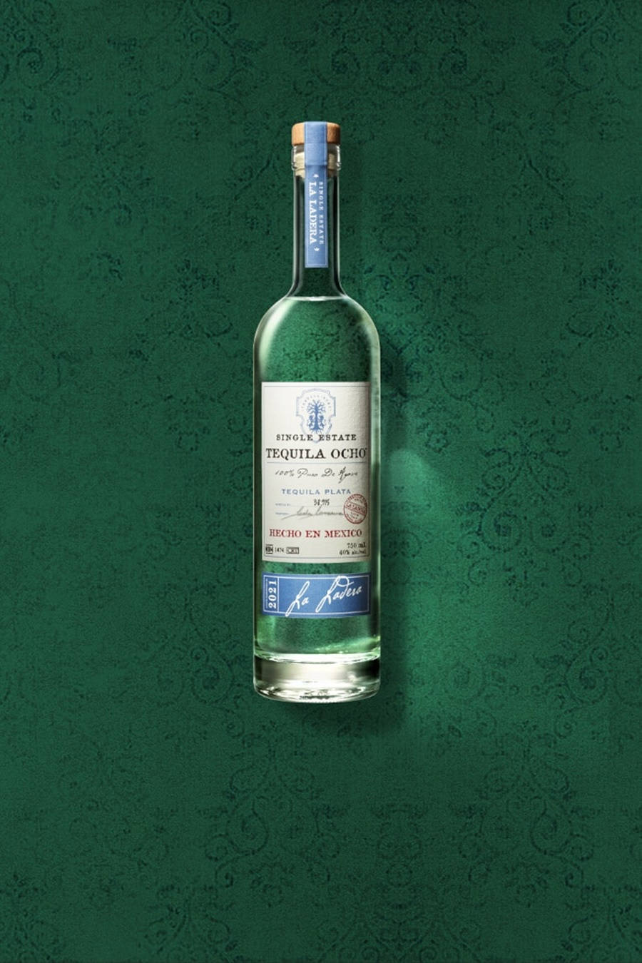 bottle 桌布 壁紙 — 一個透明的龍舌蘭酒瓶，標籤寫著 'Tequila Ocho'，位於華麗的綠色錦緞壁紙背景中央。