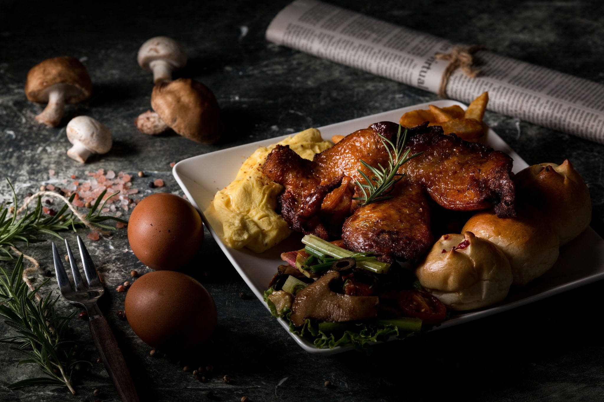 Chicken 桌布 壁紙 — 一個鄉村風格的盤子，盛有烤雞蛋、蘑菇和香草，放在深色紋理表面上，搭配報紙和迷迭香。