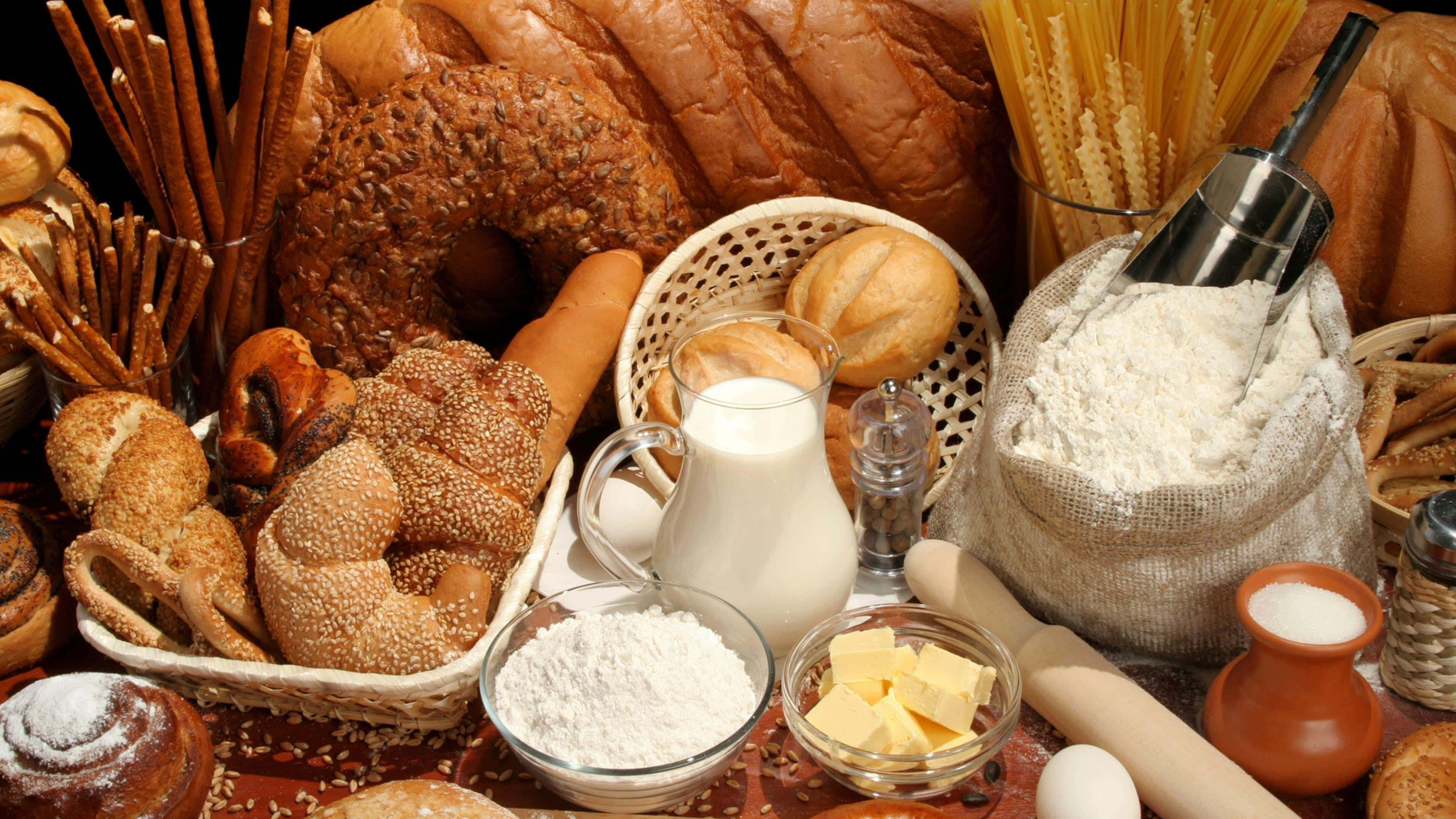 Bakery 桌布 壁紙 — 一個鄉村風格的靜物擺設，包括新鮮麵包、糕點、麵粉、牛奶、奶油和雞蛋，誘人地排列著準備烘焙。
