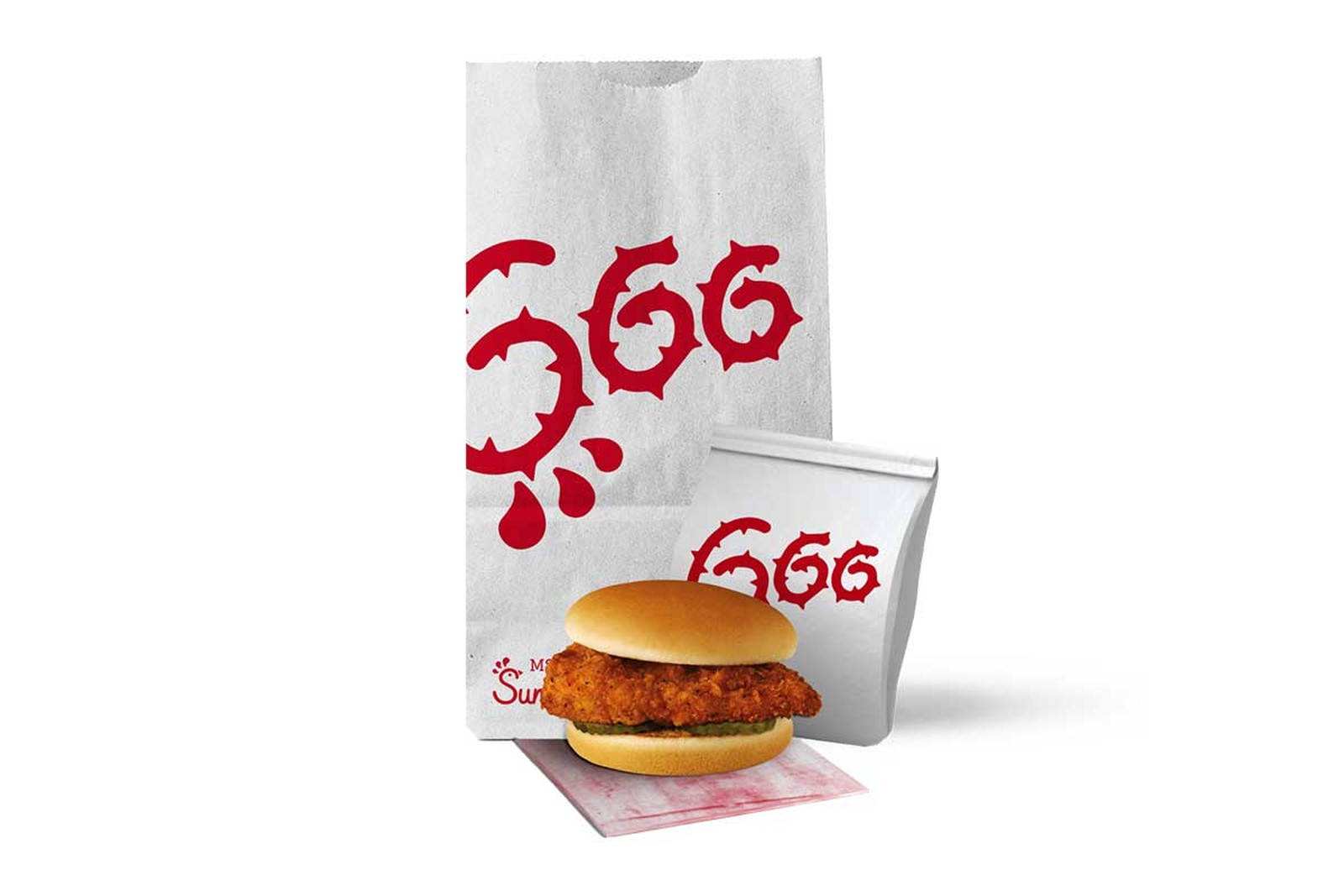 chick 桌布 壁紙 — 一個酥脆的炸雞三明治放在有品牌的餐巾上，旁邊有兩個白色紙袋，上面有粗體紅色的「GOG」標誌。