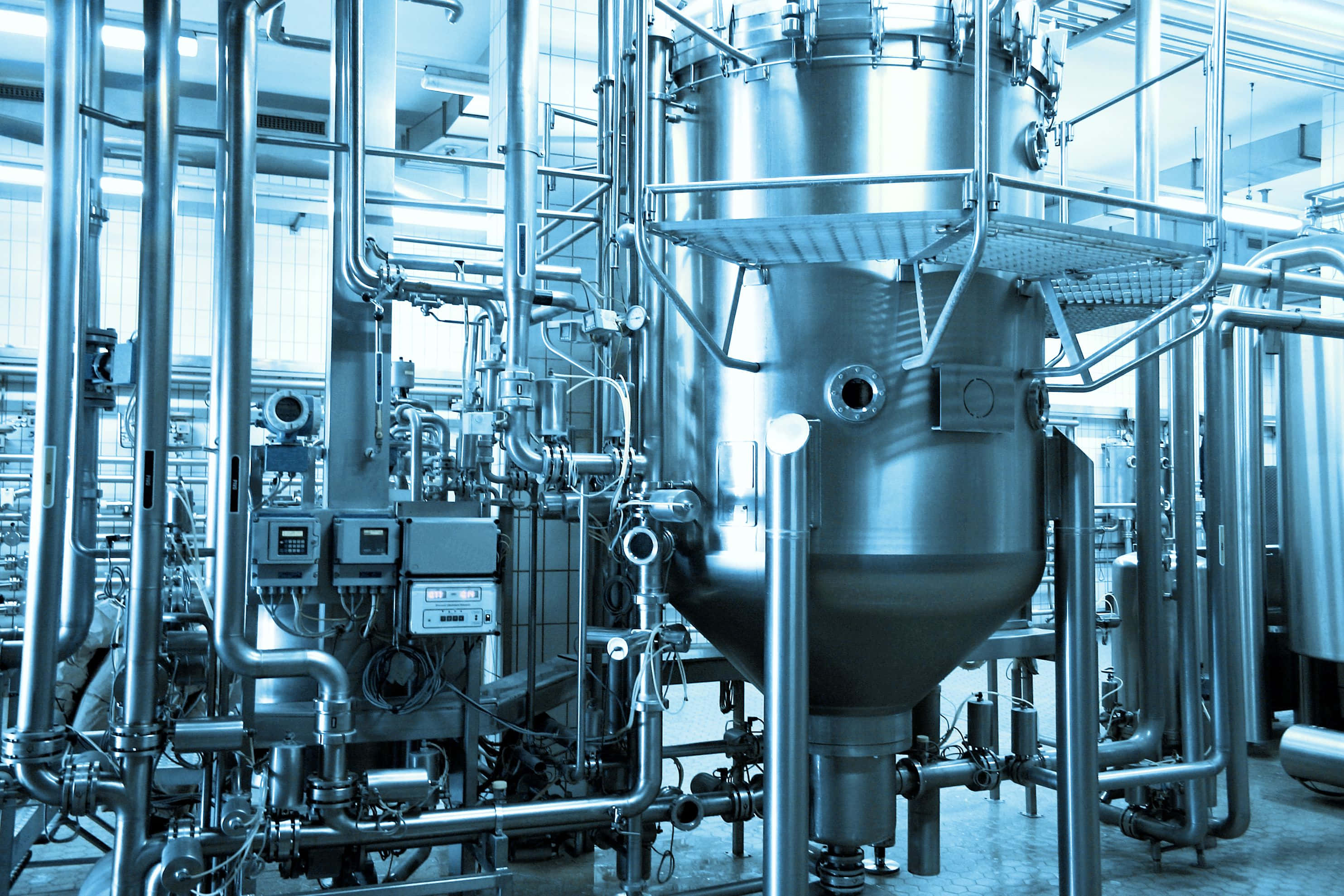 Manufacturing 桌布 壁紙 — 一個酷炫的藍色調工業啤酒廠內部，配有不鏽鋼大桶和複雜的管道系統。